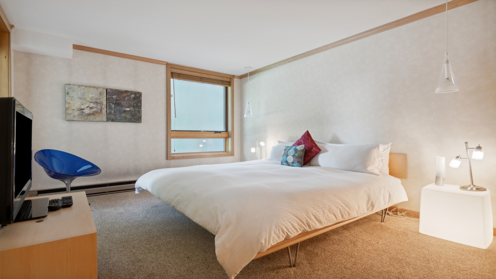 Your serene bedroom retreat features a plush king bed, modern artwork, cozy seating, and natural light streaming through large windows—perfect for restful mornings.