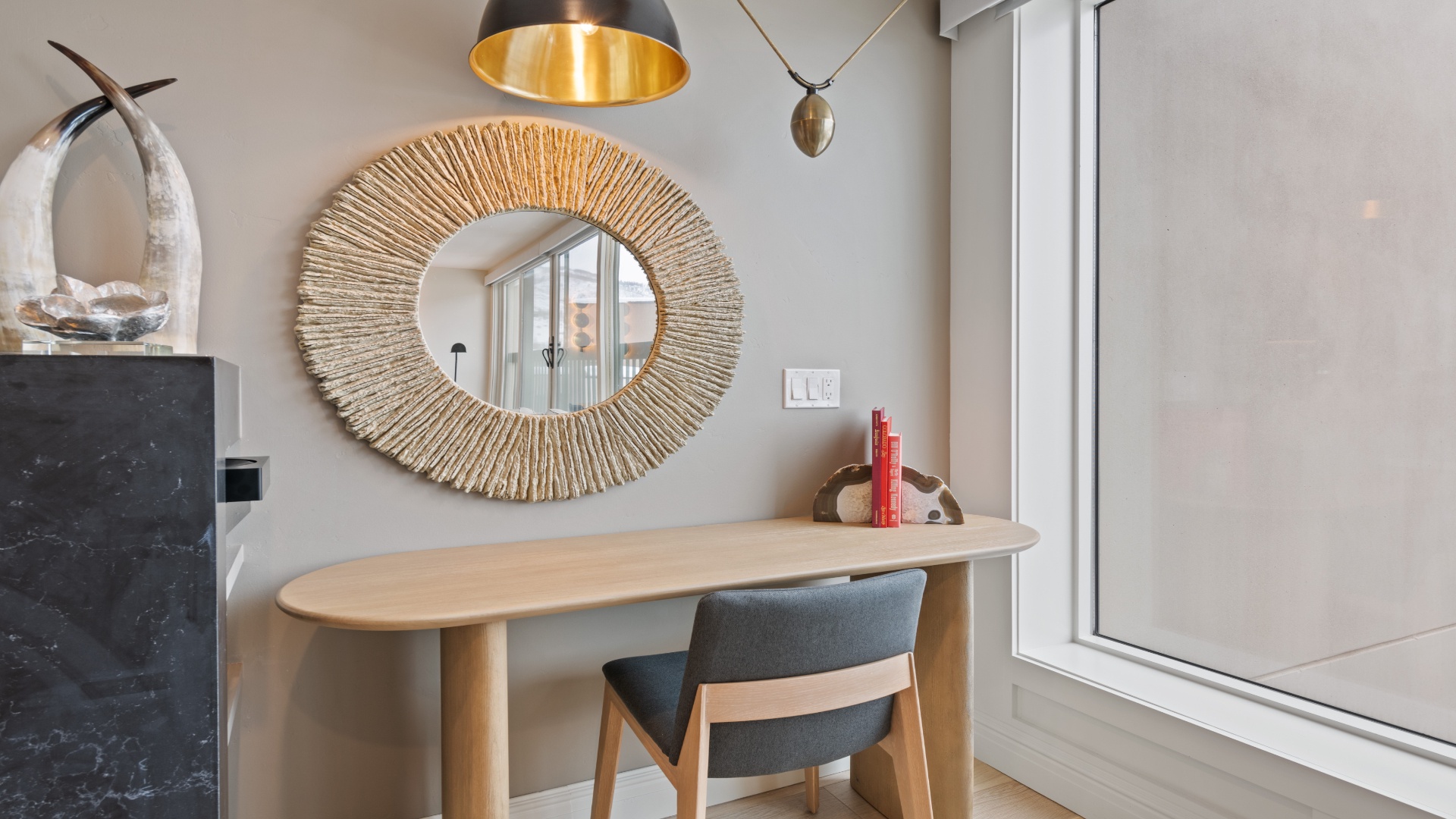 A stylish workspace awaits with a modern desk, statement mirror, and elegant lighting to inspire your creativity.