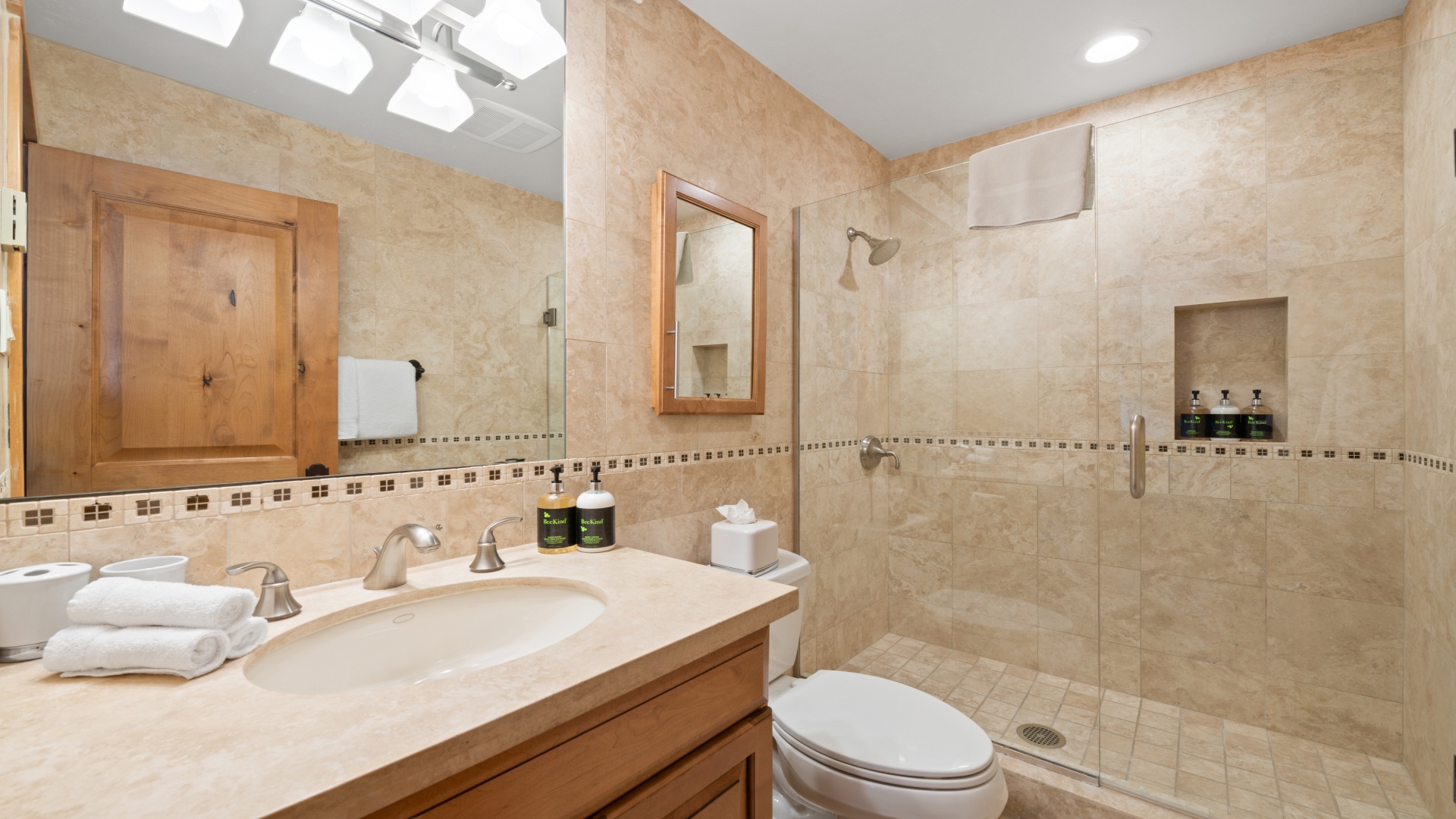 Step into your private spa-like bathroom with warm earth tones, a spacious walk-in shower, plush towels, and natural light streaming through the skylight above.