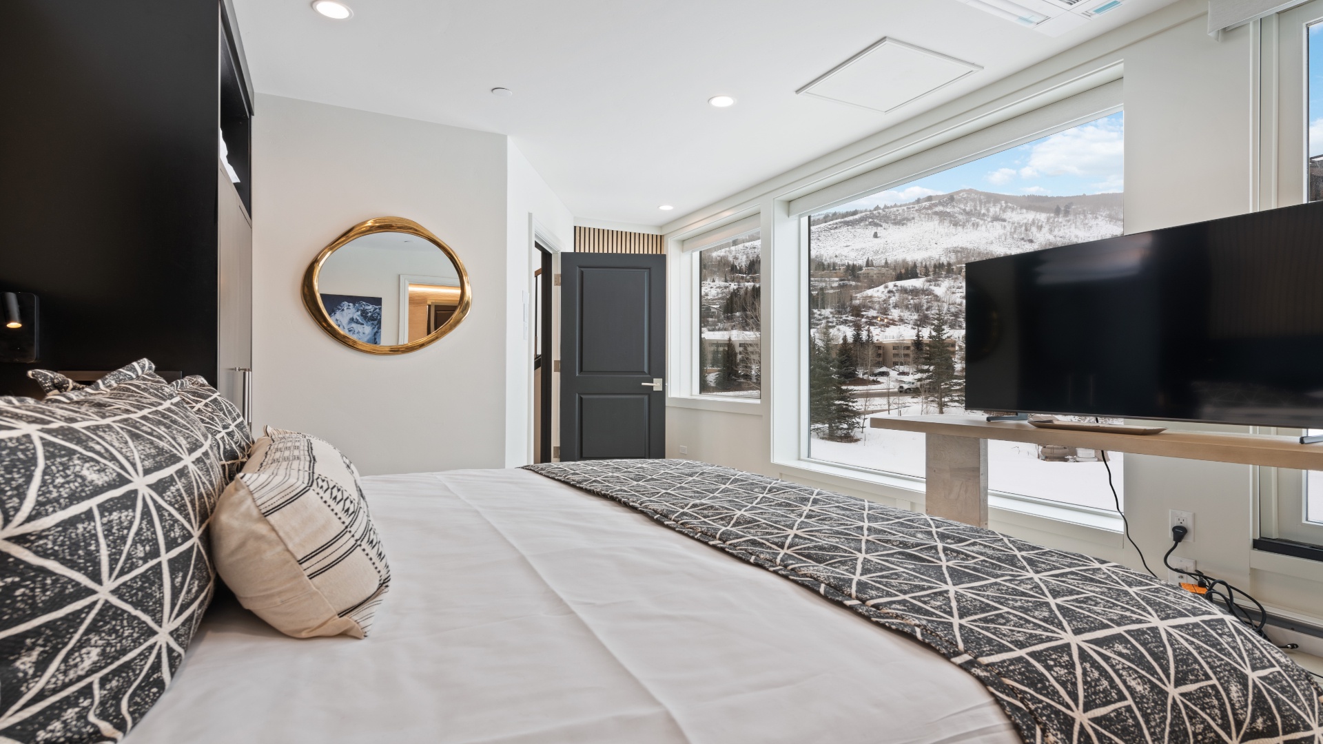 Relax in this serene bedroom where floor-to-ceiling windows frame spectacular snowy mountain views. Sink into plush bedding while enjoying modern comforts and a peaceful alpine setting just outside your window.