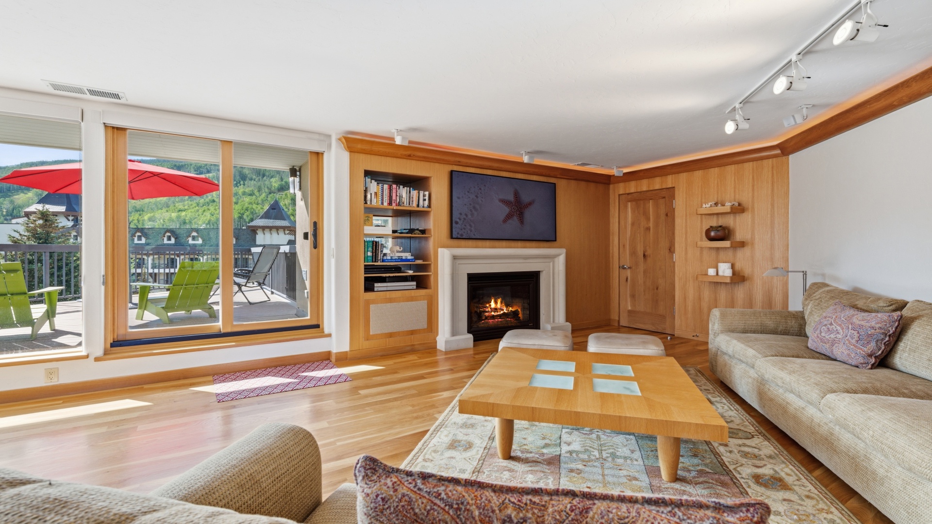 Unwind in your sunlit living room with gleaming hardwood floors, a cozy fireplace, and mountain views through expansive glass doors opening to your private deck.