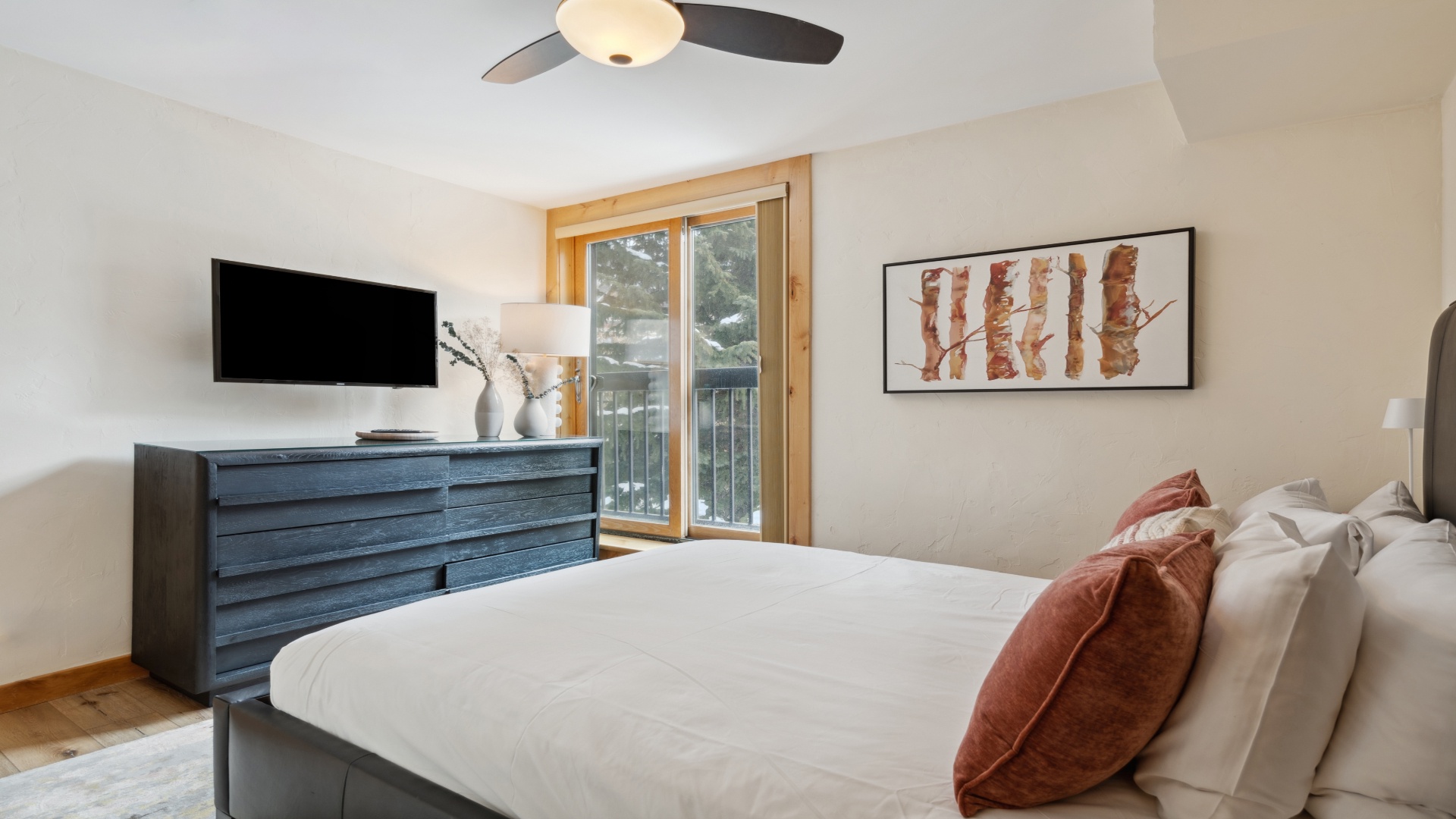 Unwind in your serene bedroom with modern mountain comfort. Crisp linens, calming artwork, and a balcony invite peaceful mornings and restful nights in your alpine retreat.