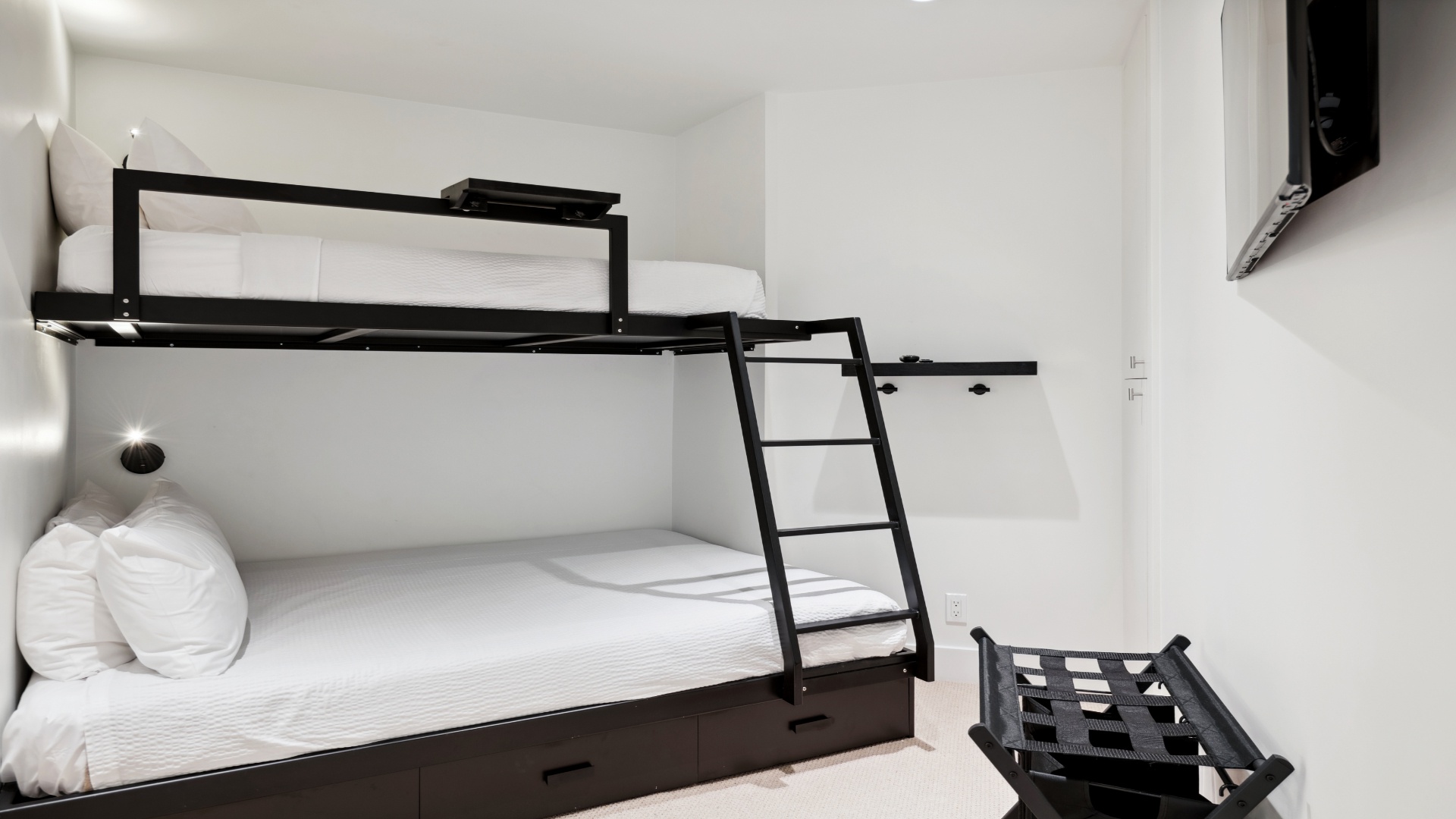 Perfect for families or groups, this modern bunk room offers clean, comfortable sleeping arrangements with crisp white linens and plenty of space for everyone to rest well.
