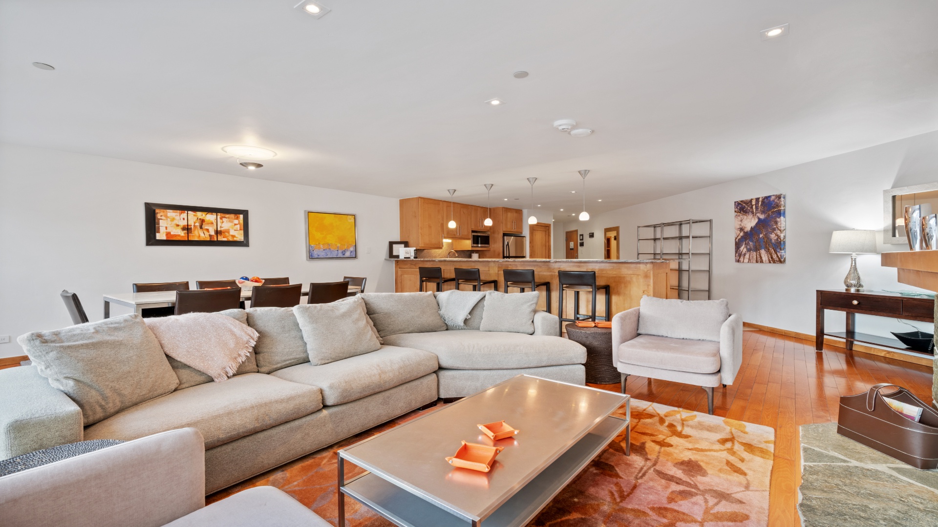 Settle into plush seating in your spacious open-plan living area, where warm wood tones, modern art, and a fully-equipped kitchen create the perfect setting for your getaway.