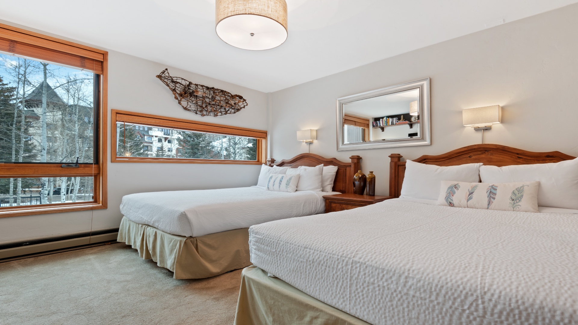 Sink into plush beds with crisp linens while natural light fills your mountain retreat through large windows overlooking snowy alpine trees and peaceful winter scenery.