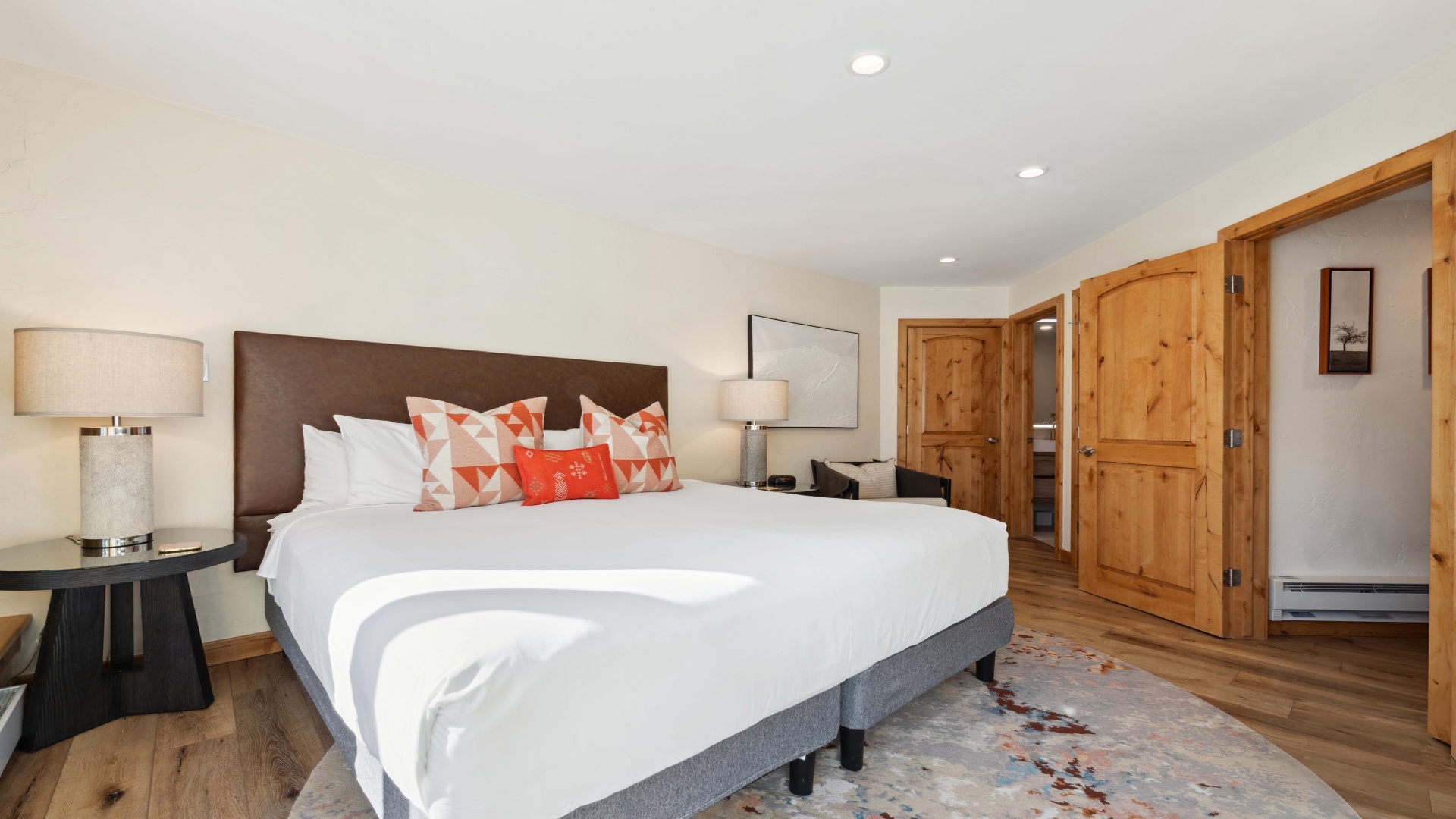 Sink into crisp white linens with vibrant accent pillows after your day of adventure. Warm wood floors and rustic doors create a cozy mountain retreat where you can truly unwind.
