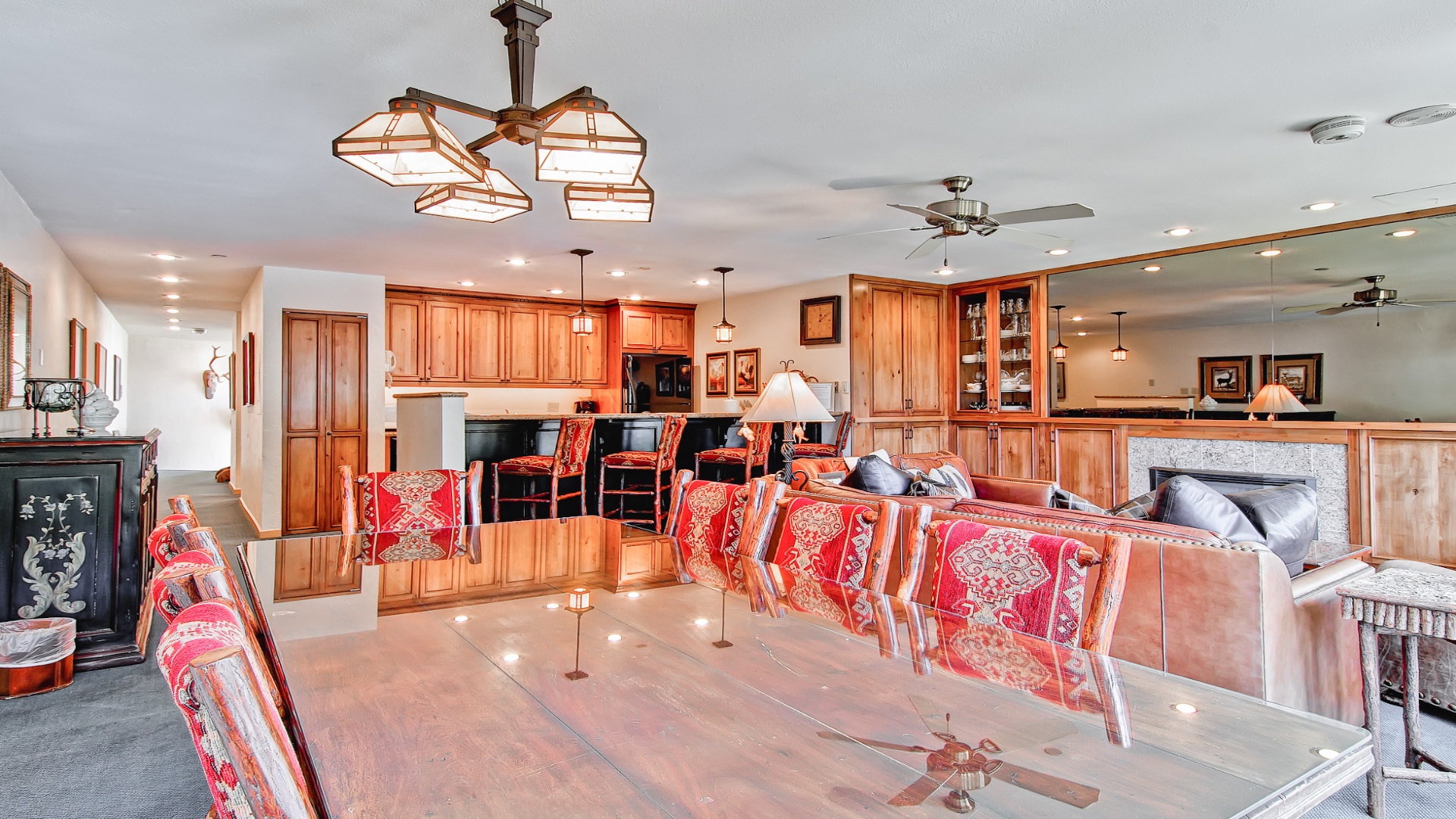 An expansive open-concept living area blends rich wood cabinetry with polished tile floors, creating a warm, welcoming space where you can cook, dine, and unwind together under elegant lighting.