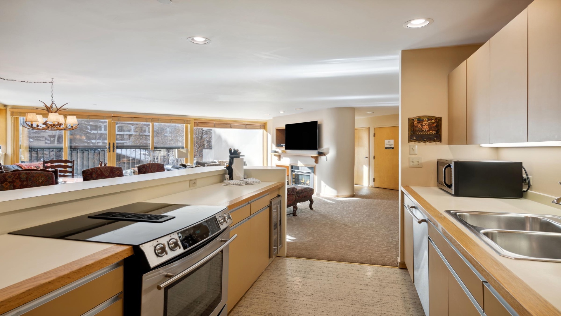 Your open-concept retreat blends a fully-equipped kitchen with a cozy living space, where sunlight pours through large windows to frame wintry views perfect for après-ski unwinding.