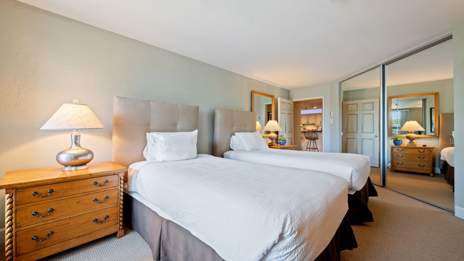 Sink into crisp white linens and rest easy in your calming retreat, where soft lighting and mirrored closets create an inviting space for relaxation.