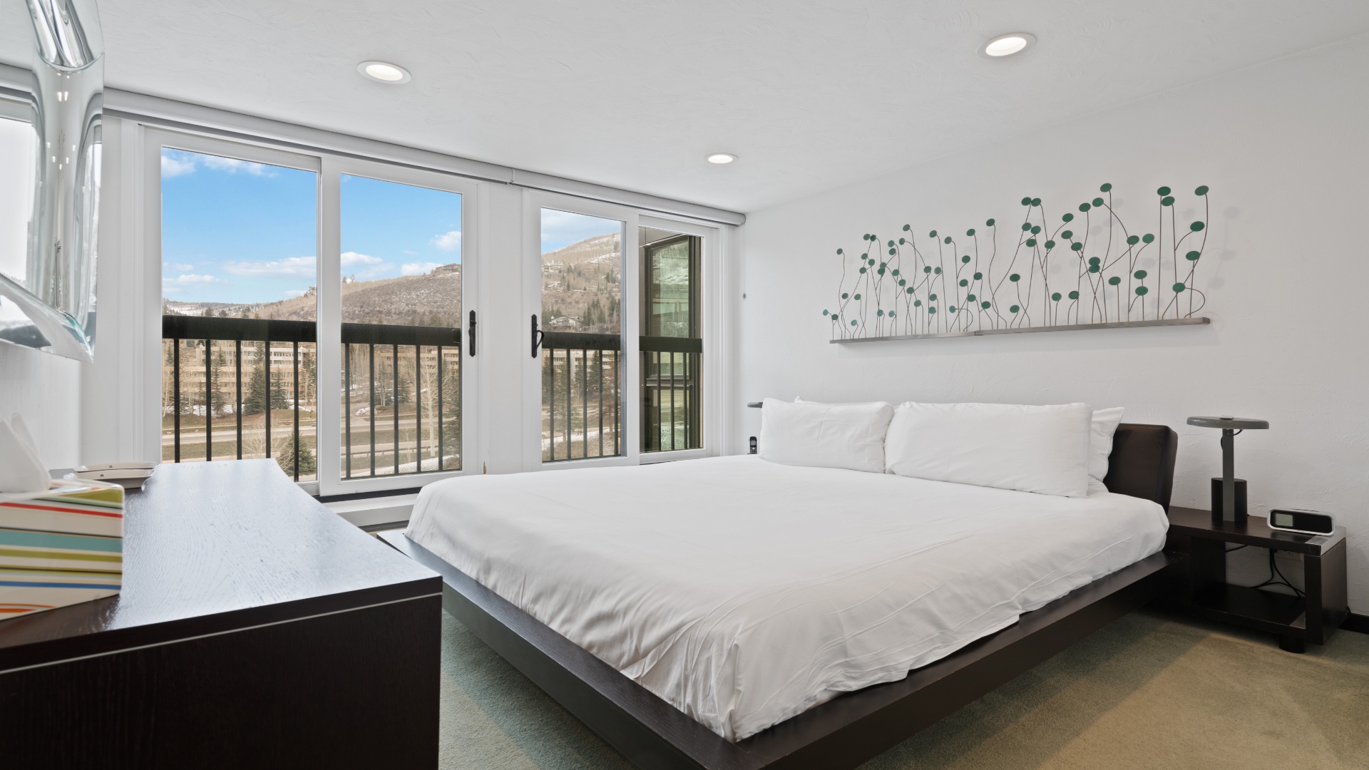 Wake up to mountain views through expansive windows framing your serene bedroom. Crisp linens, modern décor, and natural light create your perfect retreat.