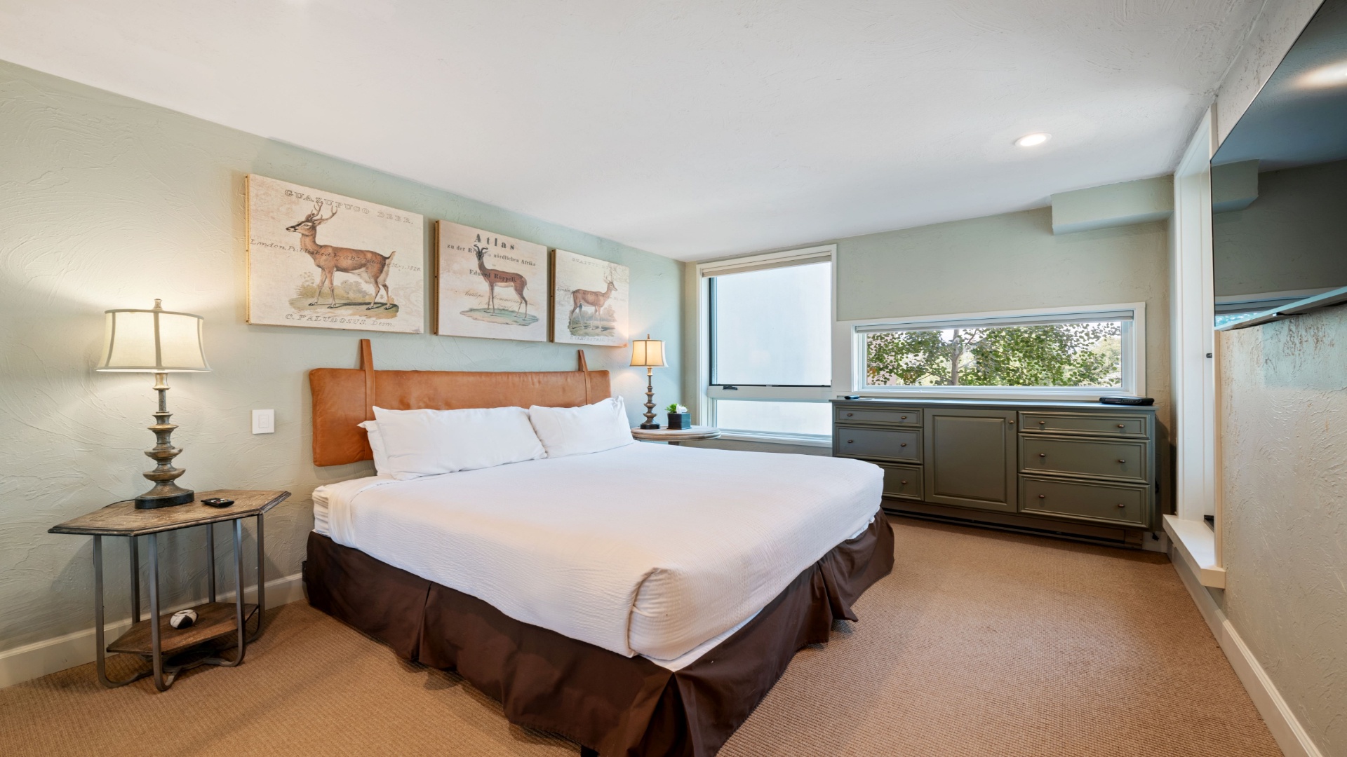 You'll find peaceful rest in this serene bedroom, with soft linens, nature-inspired artwork, and gentle natural light from large windows overlooking the trees outside.