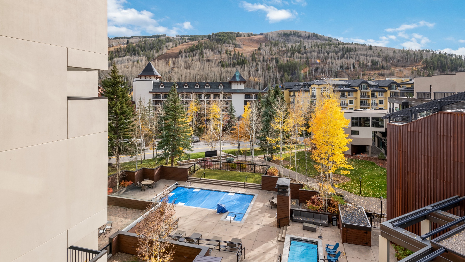 Stunning mountain resort setting with vibrant fall foliage, outdoor pools, and ski slopes rising in the background—a year-round destination where adventure meets alpine beauty.