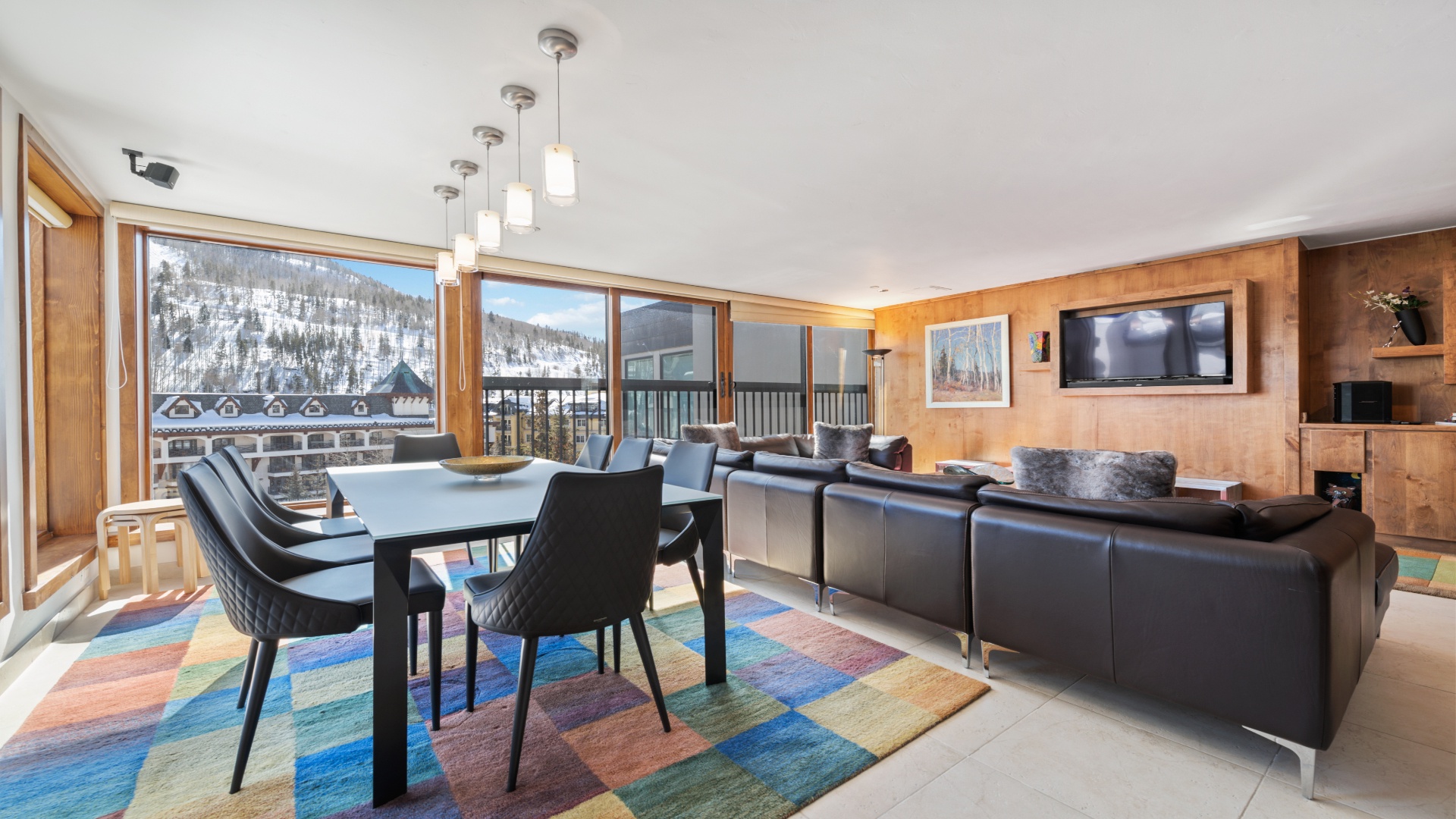 Sink into the sleek leather sofa and take in stunning snowy mountain views through floor-to-ceiling windows. Warm wood accents and modern lighting create your perfect alpine retreat.