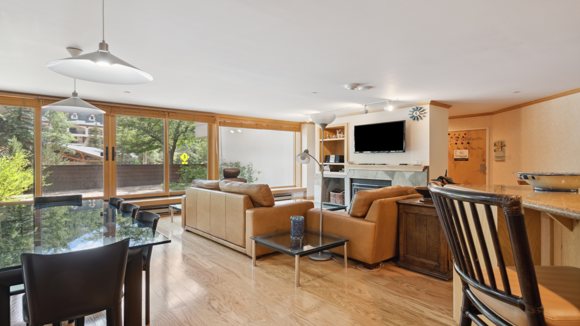 Relax in your spacious living room with sleek leather sofas, a cozy fireplace, and floor-to-ceiling windows framing lush greenery—your perfect retreat after a day of adventure.