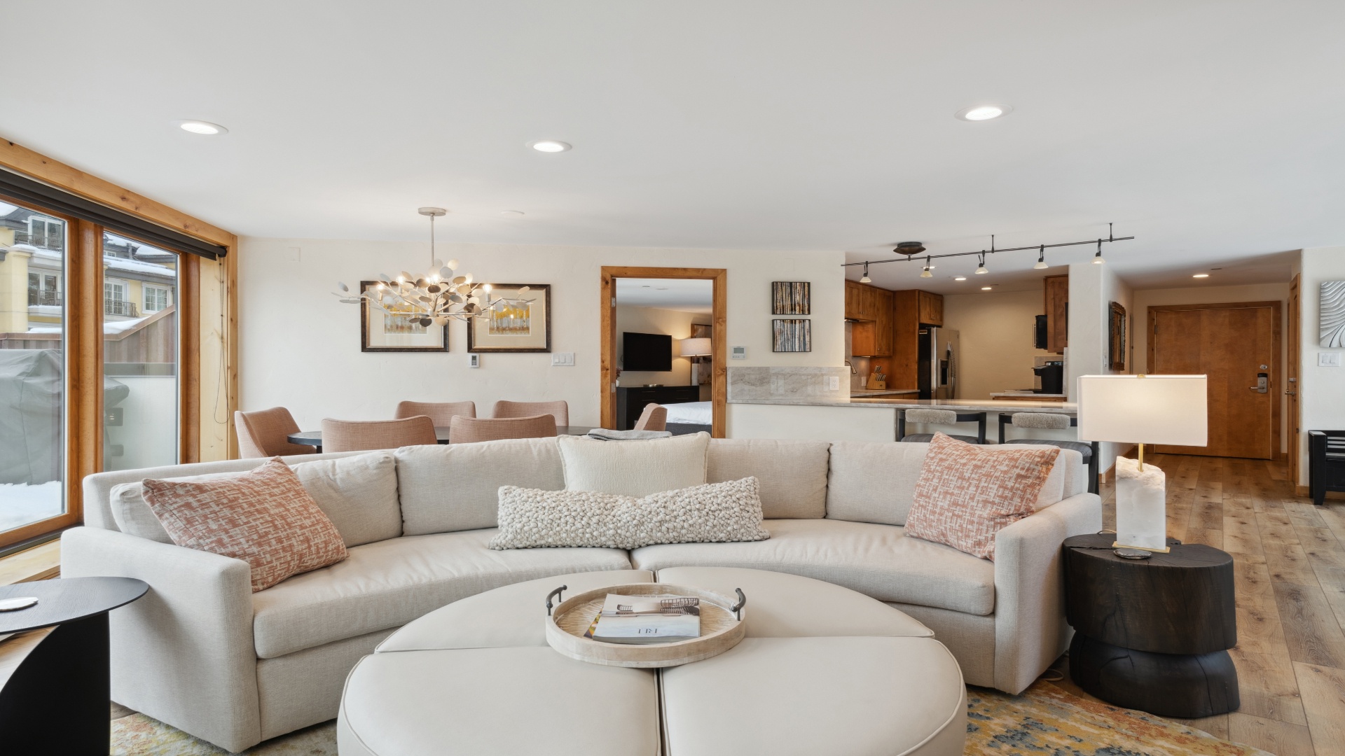 Step into an open, light-filled living space where you'll find plush seating, a sleek modern kitchen, and warm wood accents creating the perfect mountain retreat for your stay.