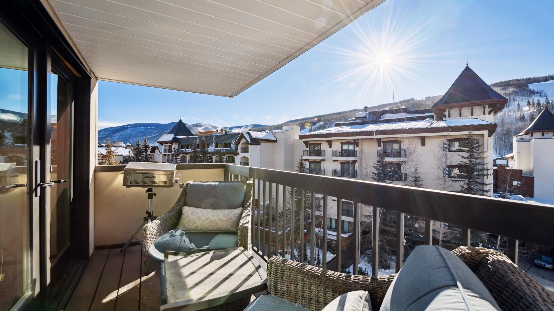The balcony offers a scenic mountain village setting, framed by snowy peaks and clear blue skies—a picturesque backdrop visible from the property's exterior terrace.
