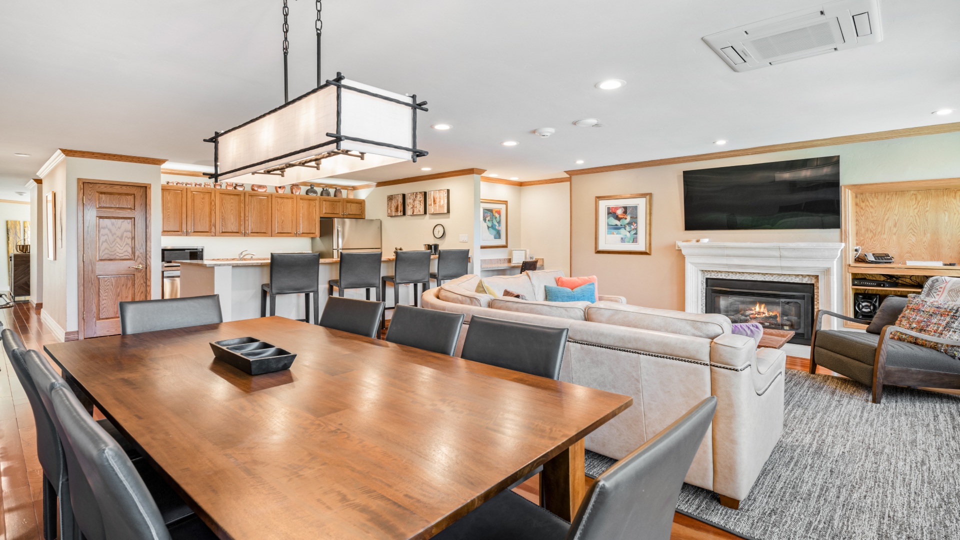 Gather around this spacious dining table where your group can share meals and stories. The open-concept layout connects you to the kitchen, cozy fireplace, and plush seating—perfect for togetherness.
