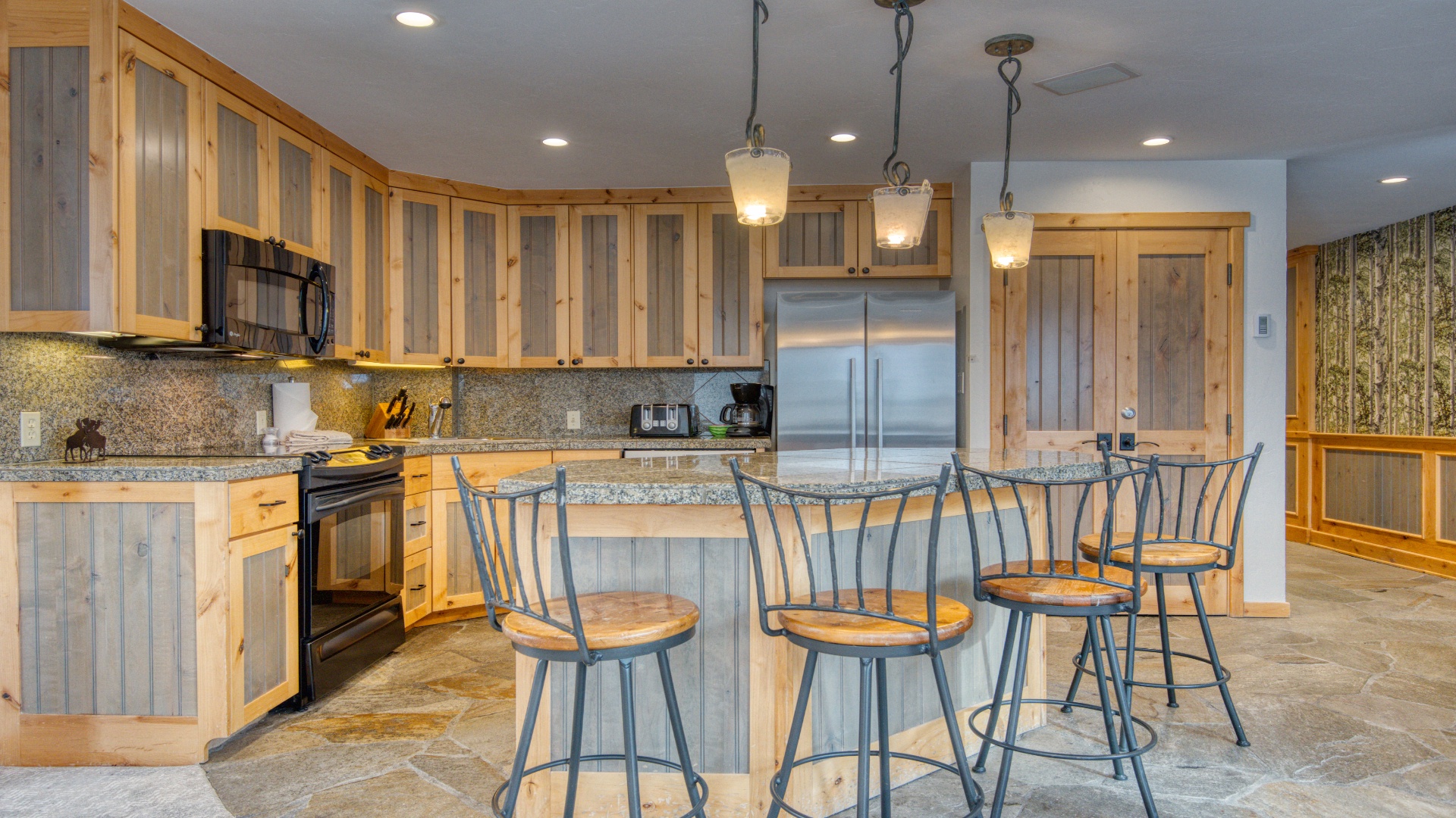 Your spacious gourmet kitchen awaits, featuring rustic two-tone cabinetry, granite countertops, stainless steel appliances, and a welcoming island with seating for five—perfect for gathering over morning coffee or preparing memorable meals together.