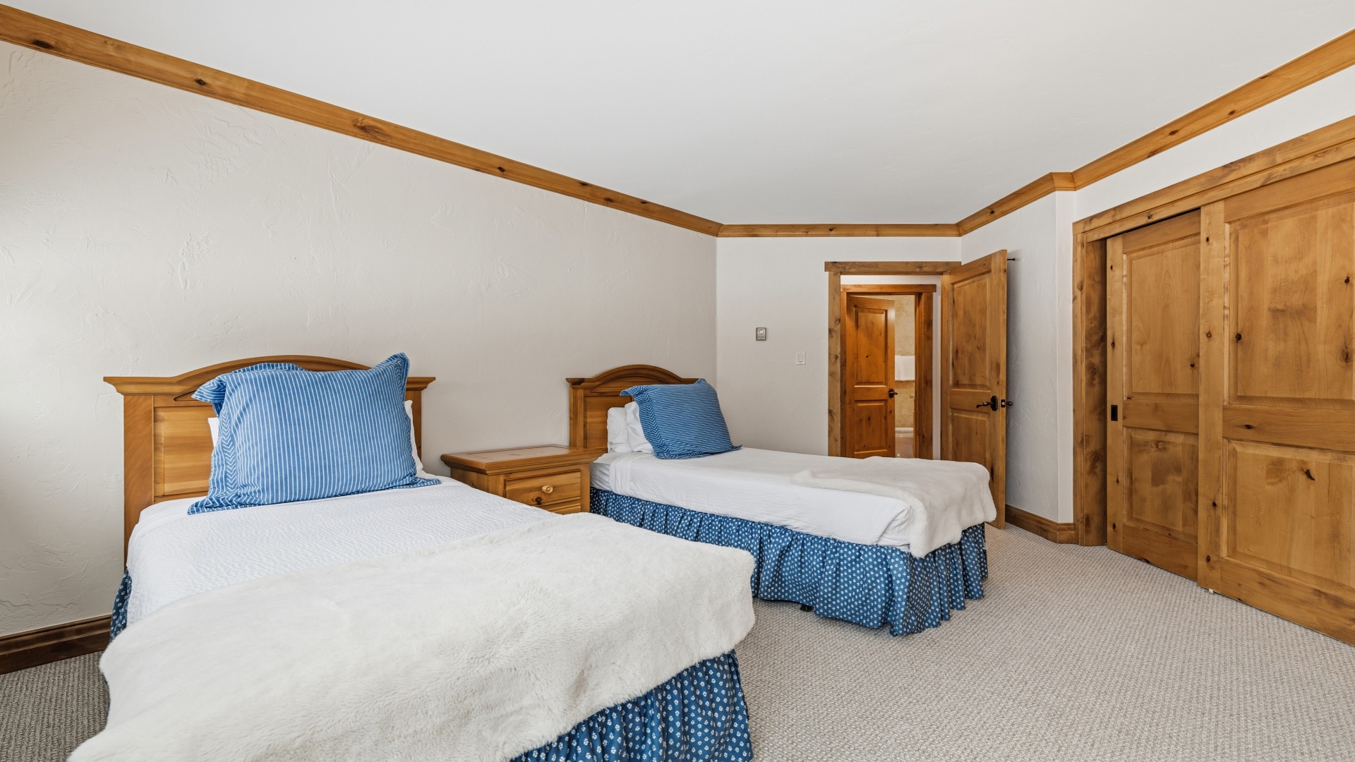 Your peaceful twin bedroom features warm wood accents and cozy blue details, offering a restful space to unwind after exploring the area.