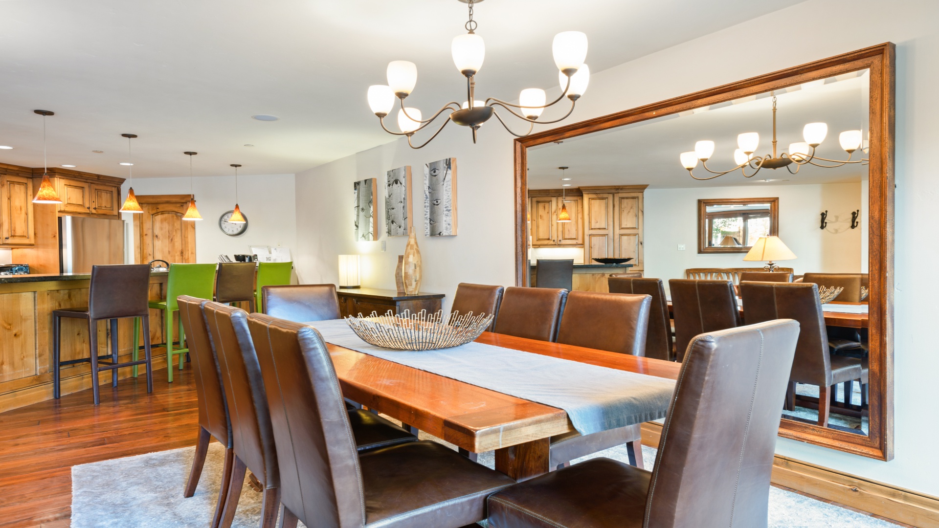 Gather around this spacious dining table, where natural wood warmth meets modern comfort under elegant lighting. The open layout connects you to the kitchen, perfect for shared meals and conversations.