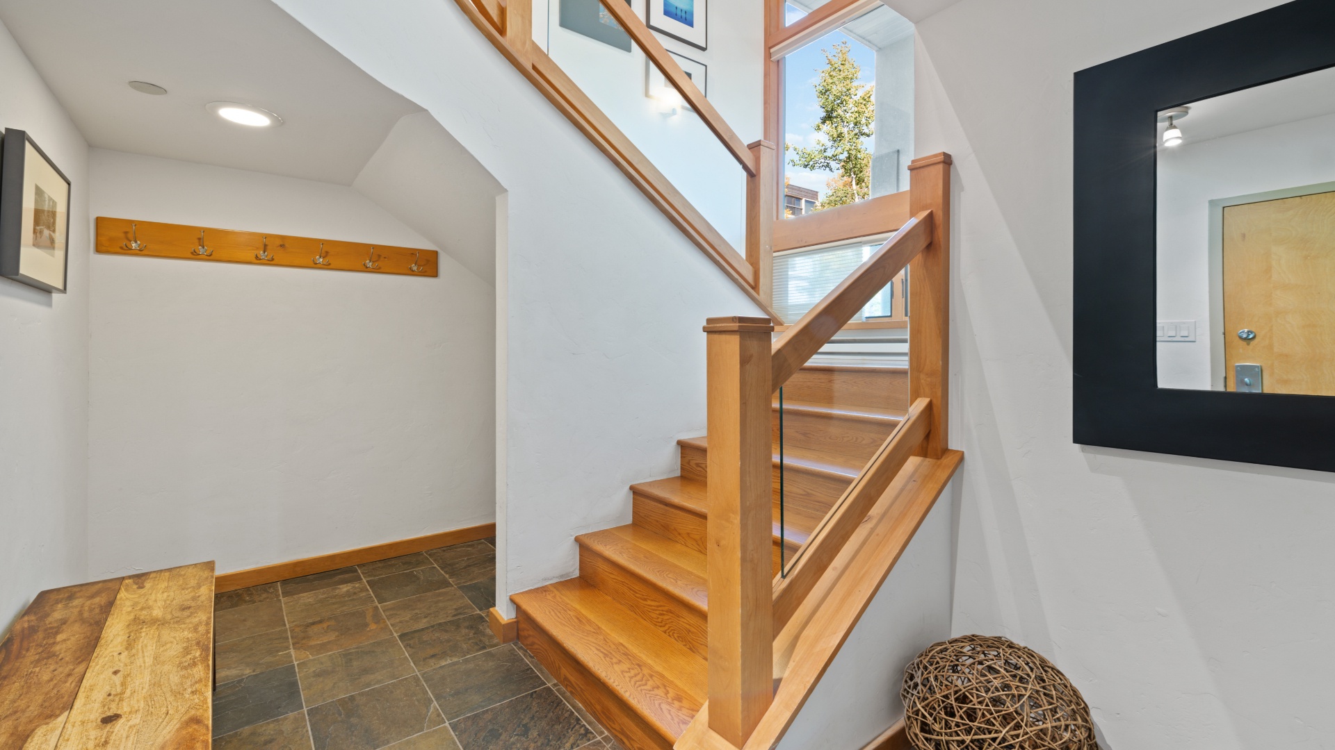 Step inside to find a bright, welcoming entryway with natural light streaming through skylights above beautiful wooden stairs that invite you to explore your vacation home.