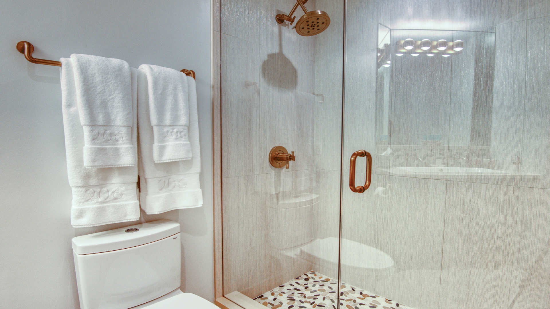 Step into your beautifully appointed bathroom, where warm copper fixtures complement crisp white towels and a spacious walk-in shower awaits your morning refresh.