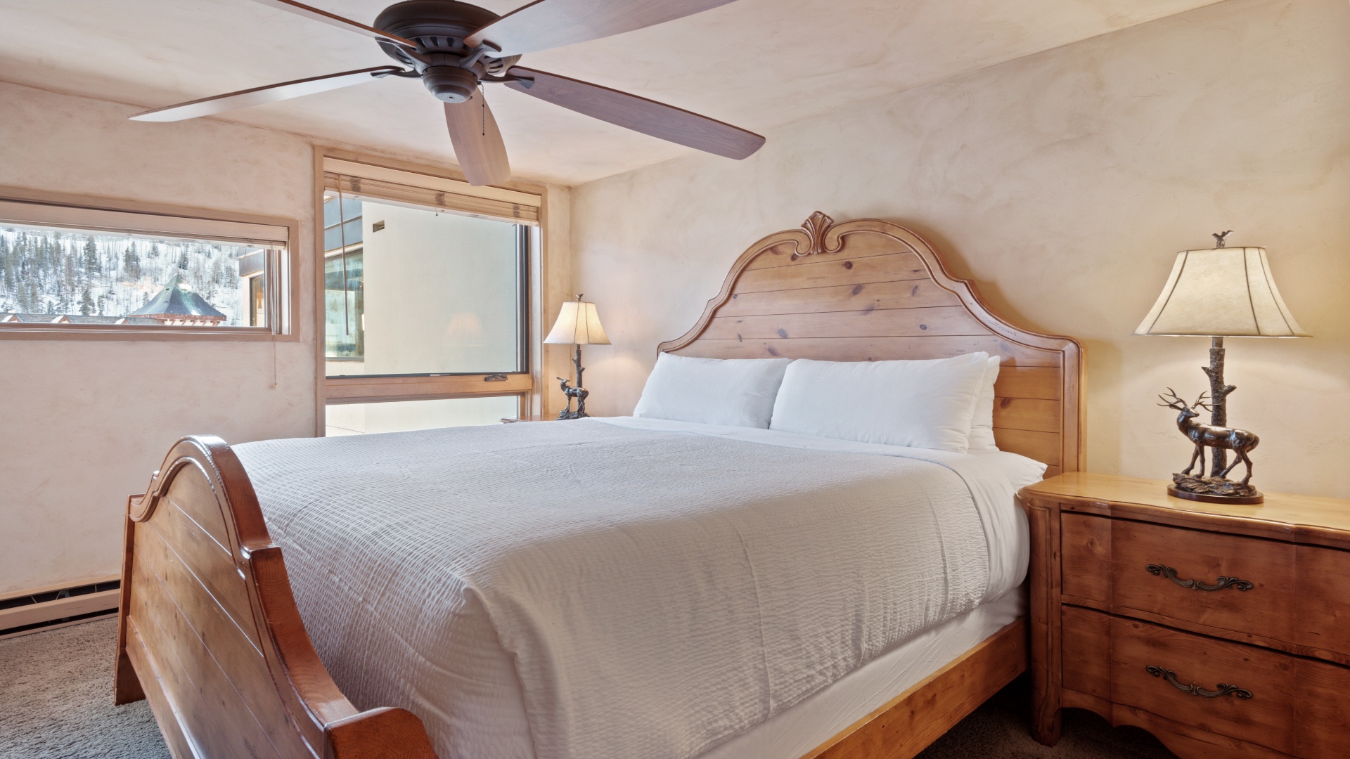 Sink into the plush comfort of your bed beneath a gentle ceiling fan, with crisp linens and charming rustic wood accents welcoming you to unwind after a day of mountain adventure.