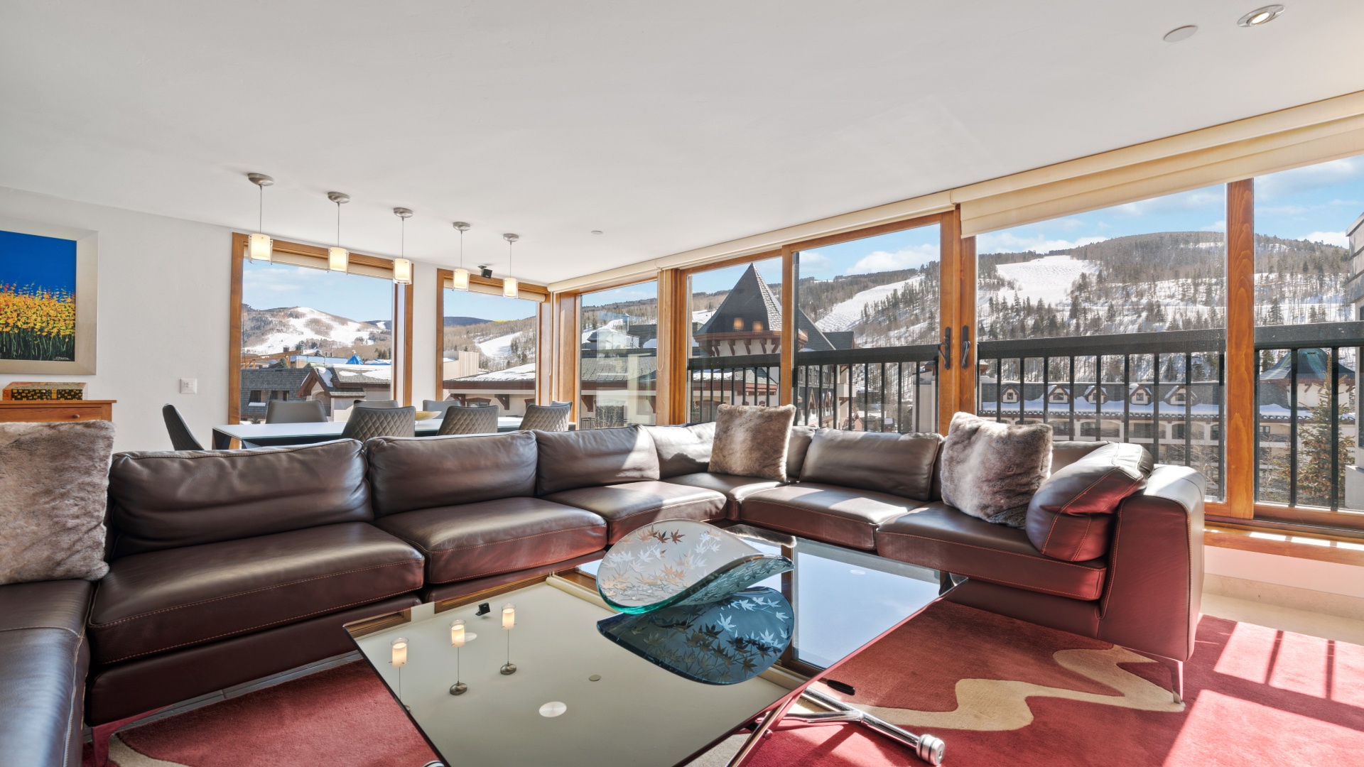 Relax on plush leather seating as natural light pours through floor-to-ceiling windows, framing breathtaking mountain views. Your perfect alpine retreat awaits with space to unwind and memories to make.