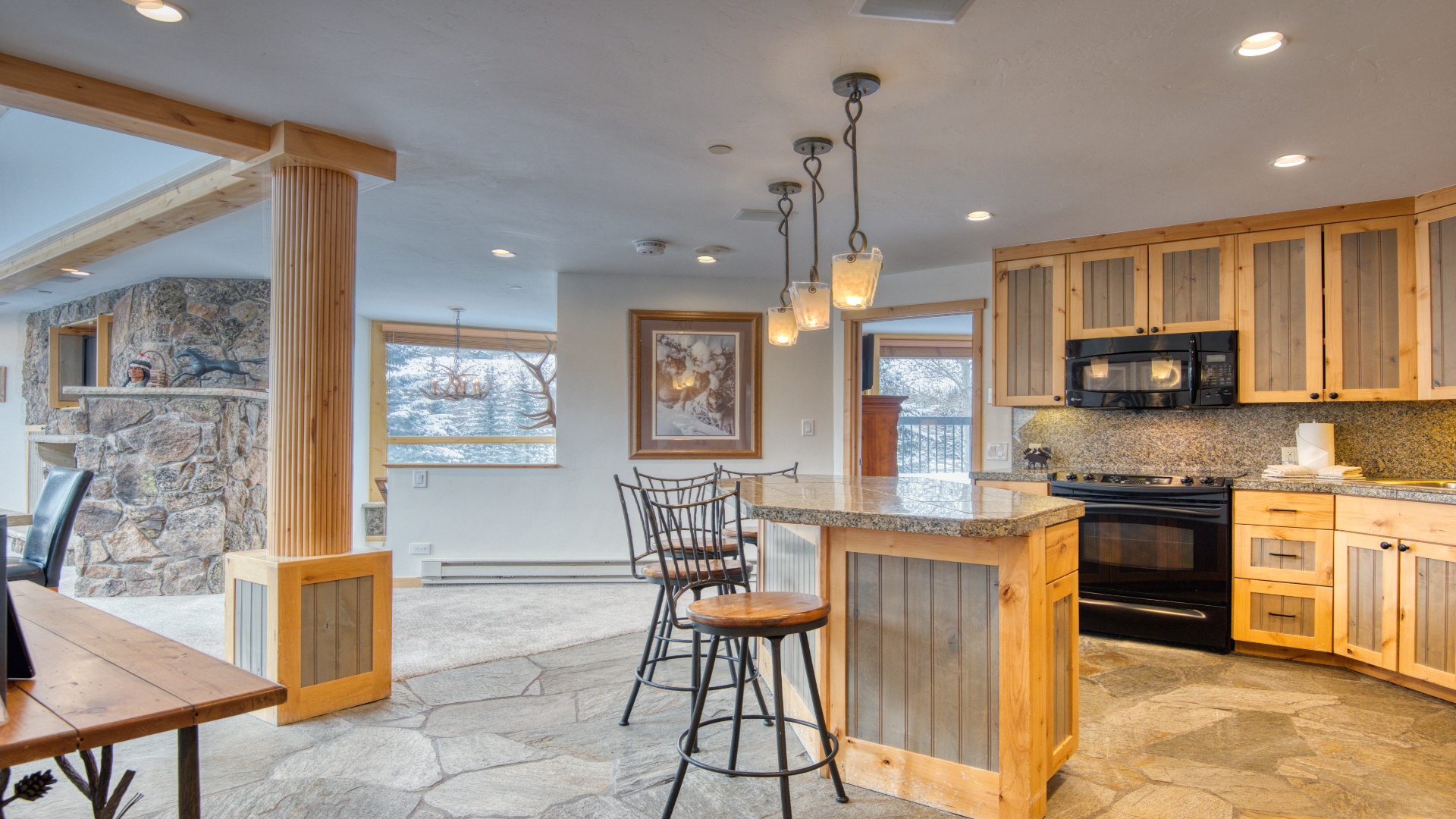 Gather around your spacious kitchen island with granite countertops, custom wood cabinetry, and modern appliances, all brightened by natural light and views of the surrounding winter landscape.