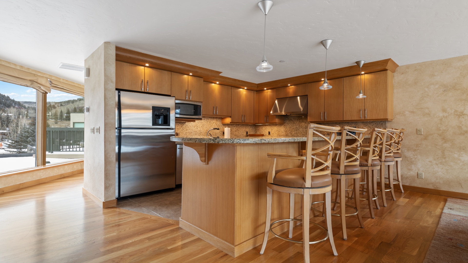Your gourmet kitchen invites culinary creativity with granite counters, modern appliances, and a spacious breakfast bar perfect for morning coffee or evening wine with mountain views beyond.