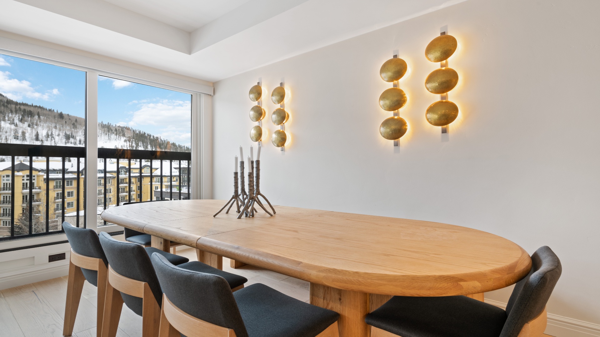 Gather around this stunning dining table where your group can share meals while soaking in snowy mountain views through floor-to-ceiling windows. Warm lighting and modern design create the perfect atmosphere.