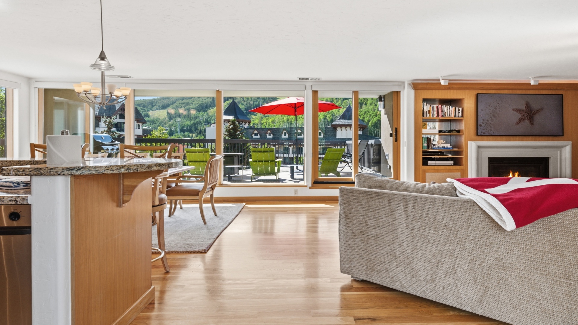 Step into your open-concept retreat where the living room flows seamlessly into the kitchen, all framed by floor-to-ceiling windows that flood the space with natural light and reveal stunning mountain views beyond your private balcony.