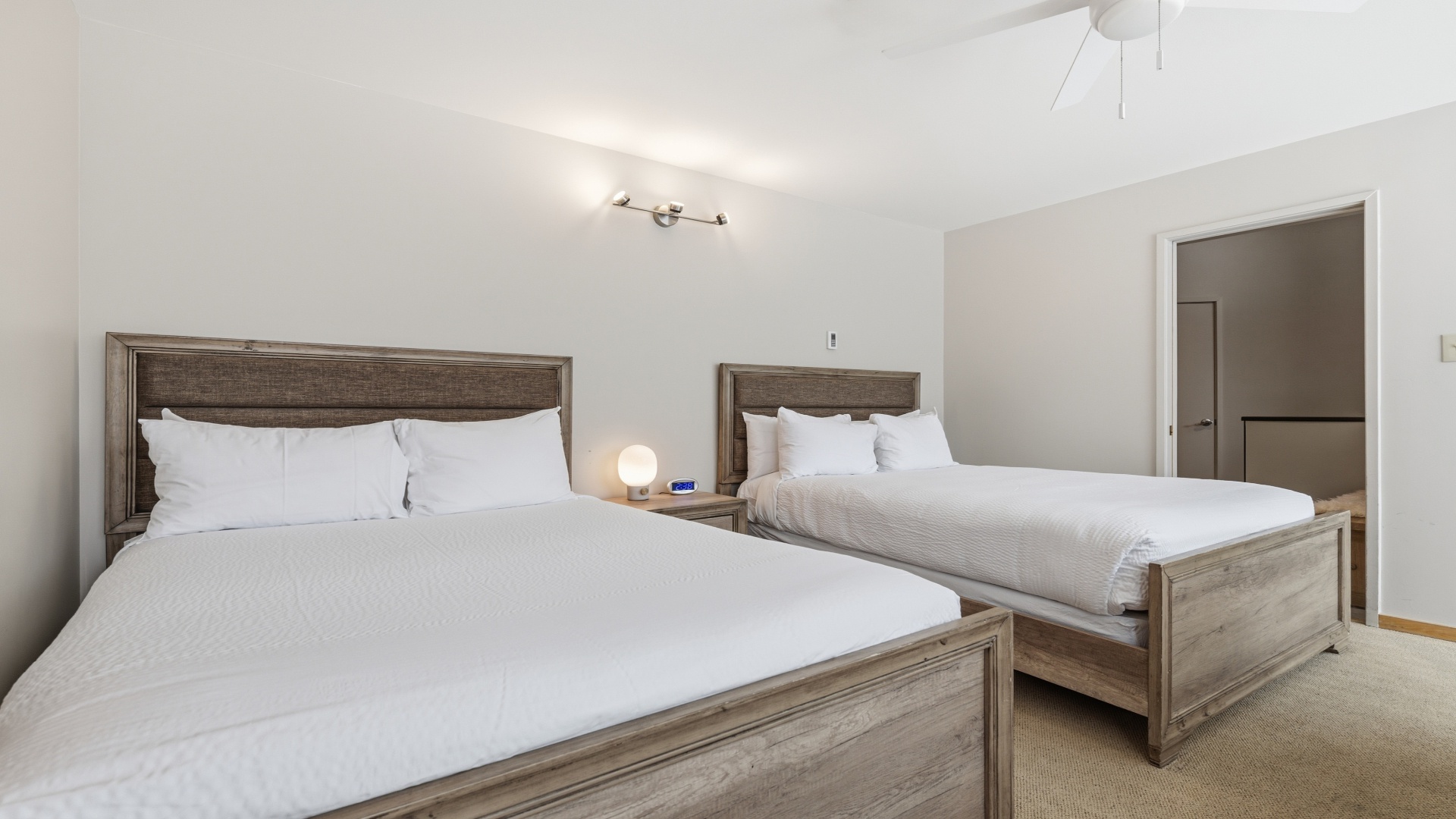Unwind in your serene bedroom with two plush queen beds dressed in crisp white linens, perfect for restful nights after your day's adventures.