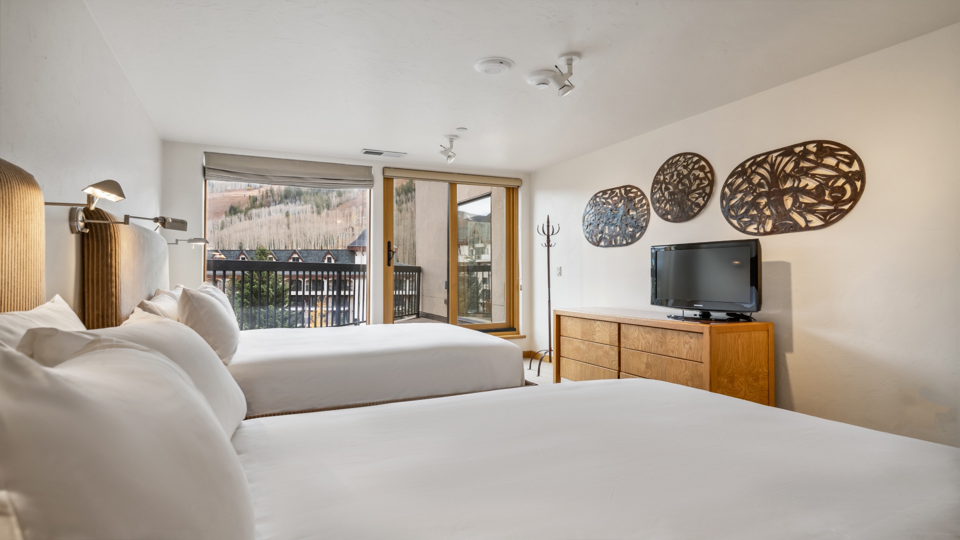 Your bright, modern bedroom features plush beds, stylish décor, and a private balcony opening to scenic mountain views—perfect for restful mornings and peaceful evenings.