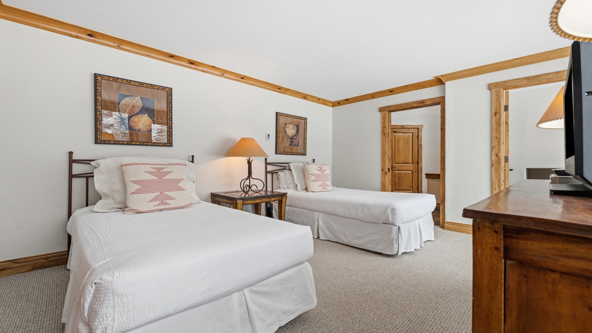 Sink into crisp white linens in your serene twin bedroom, where warm wood accents and soft lighting create a cozy mountain retreat. Your spacious room opens to connecting areas, perfect for family or friends traveling together.