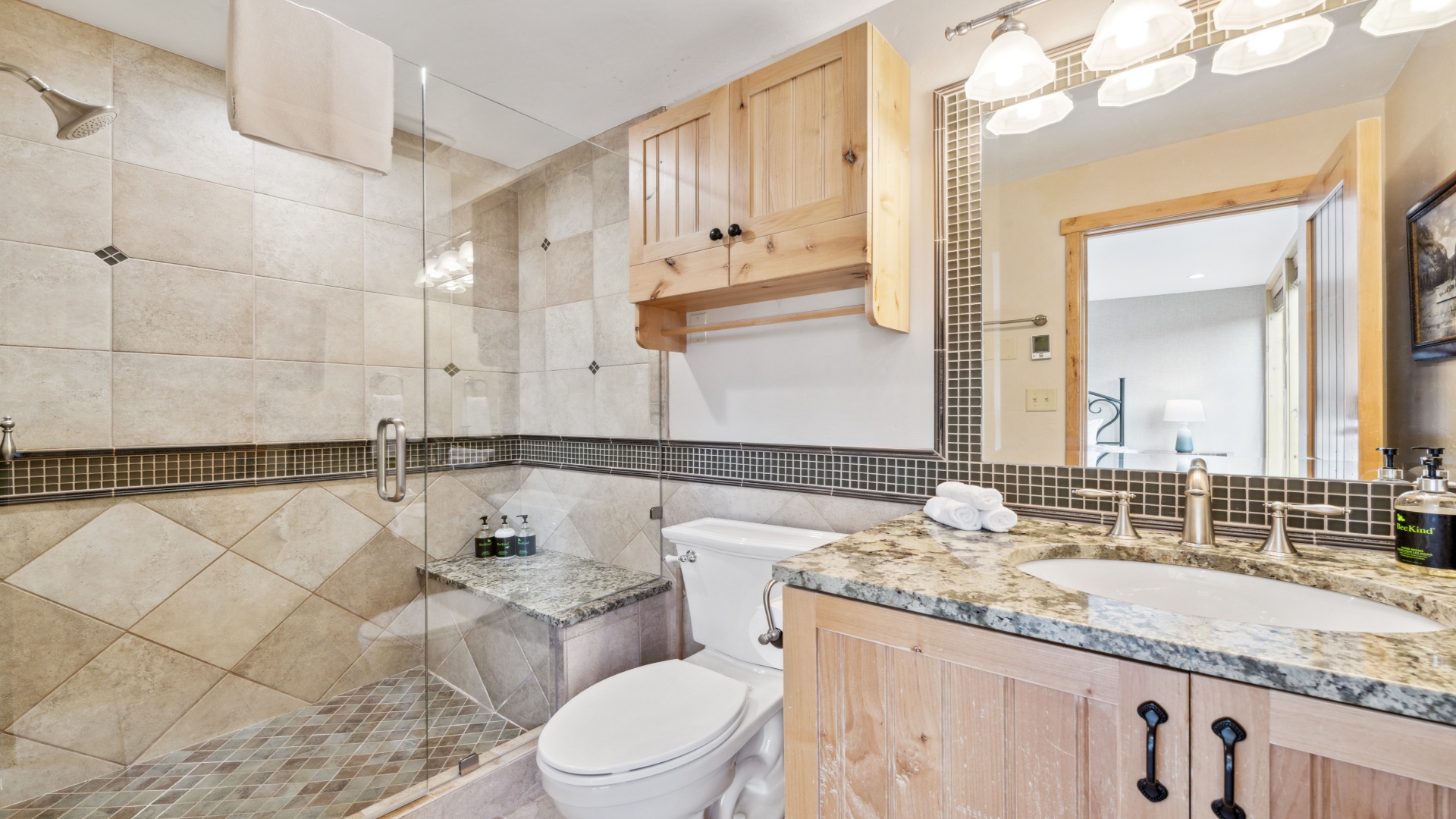 Step into your beautifully appointed bathroom featuring elegant tile work, a spacious walk-in shower, granite countertops, and warm wood cabinetry—everything you need to refresh and unwind.