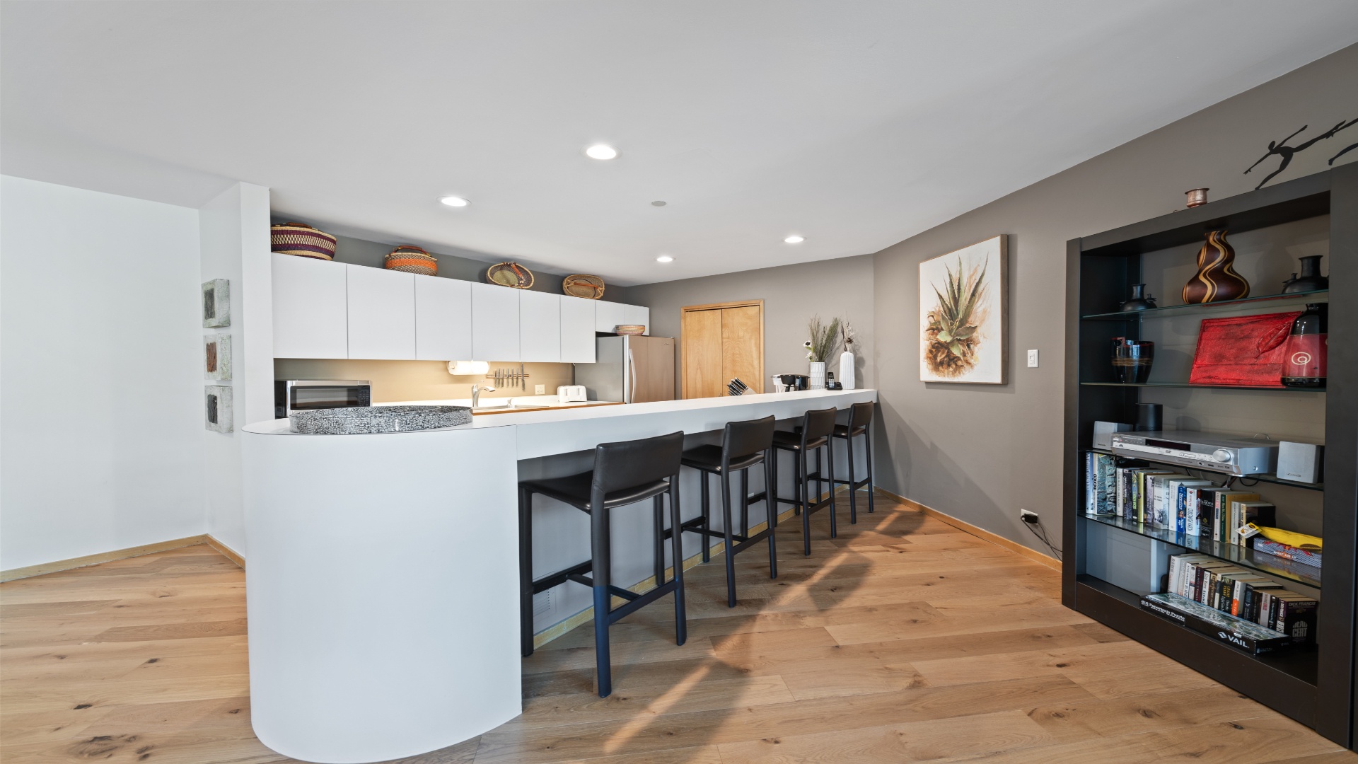 Your open-concept kitchen and dining area invites easy entertaining with a spacious breakfast bar, sleek white cabinetry, modern appliances, and warm wood floors throughout.