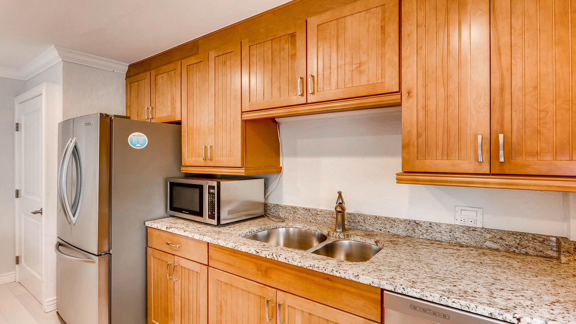 A fully equipped kitchen with granite countertops, stainless steel appliances, and warm wood cabinetry provides everything you need to prepare meals during your stay.