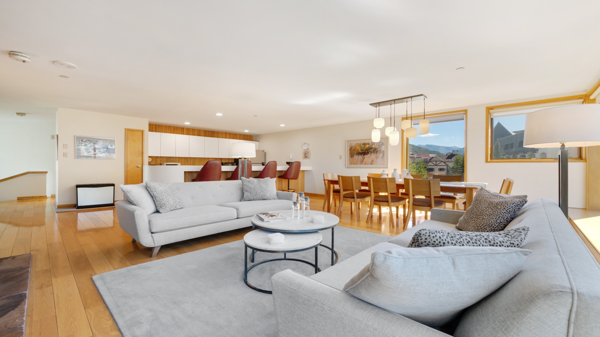 Sink into plush sofas in your bright, open-plan living space where warm wood accents meet modern style. Gather at the dining table, prepare meals in the sleek kitchen, and enjoy stunning mountain views.
