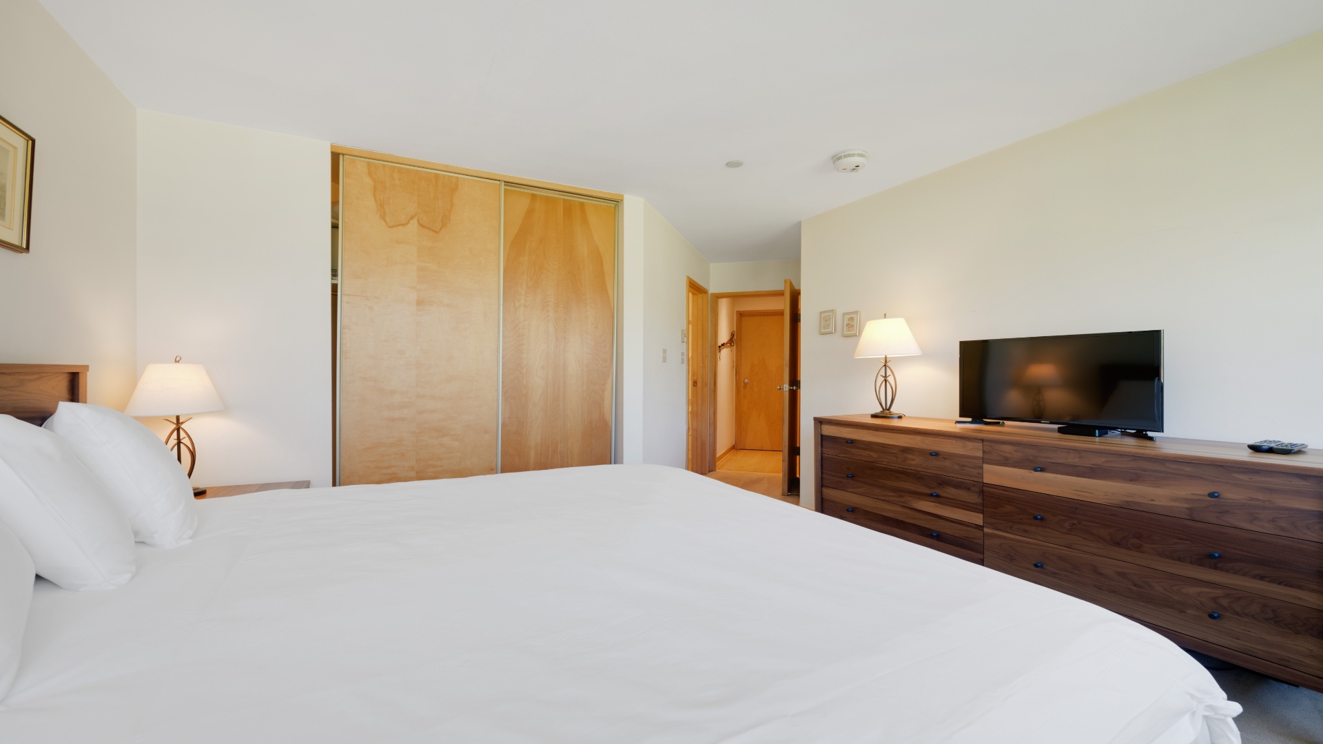 Sink into crisp white linens and unwind in your peaceful bedroom, complete with warm wood furnishings, bedside lamps for late-night reading, and entertainment at your fingertips.