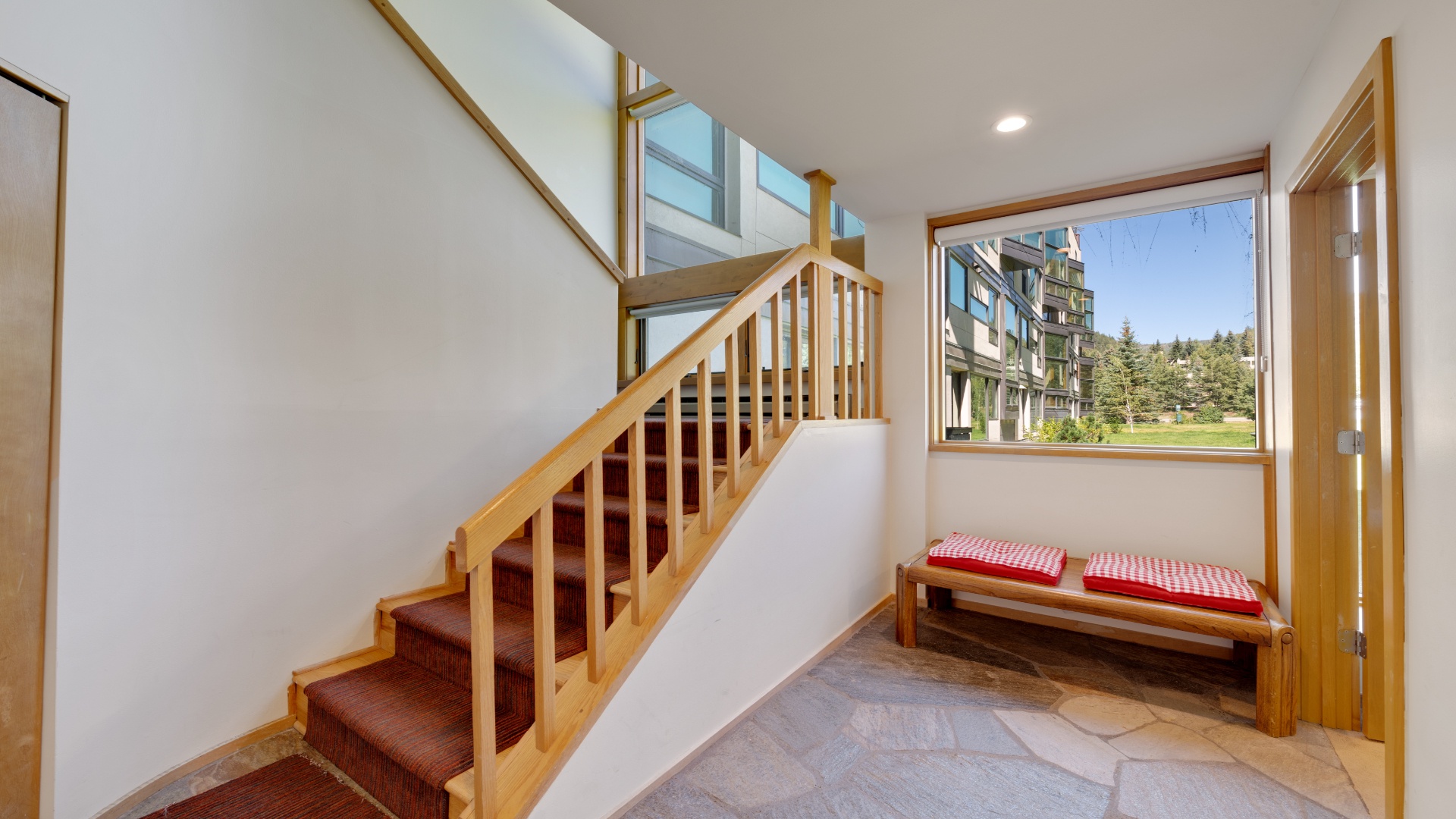 Bright, inviting entryway with a charming wooden staircase and built-in bench by the window—perfect for kicking off your mountain adventures.