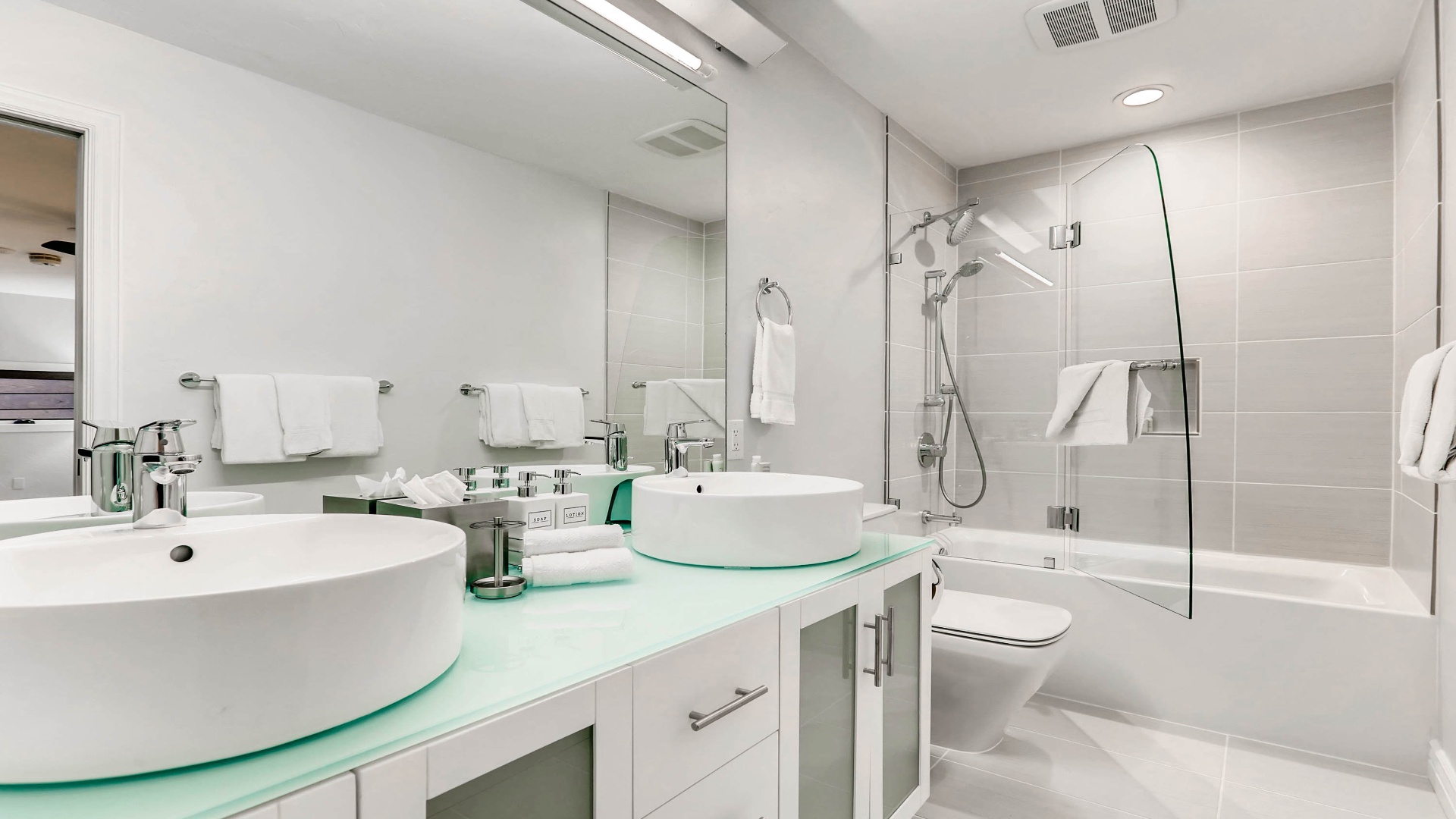 Step into your bright, modern bathroom with dual vessel sinks, a spacious tub-shower combo, and fresh towels ready for you. The glass countertop and sleek fixtures create a spa-like feel you'll love.