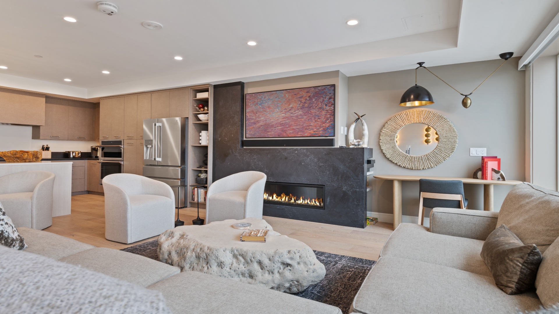 Relax in your spacious living area featuring a sleek modern fireplace, elegant artwork, and plush seating. The open layout connects effortlessly to a gourmet kitchen—perfect for your stay.
