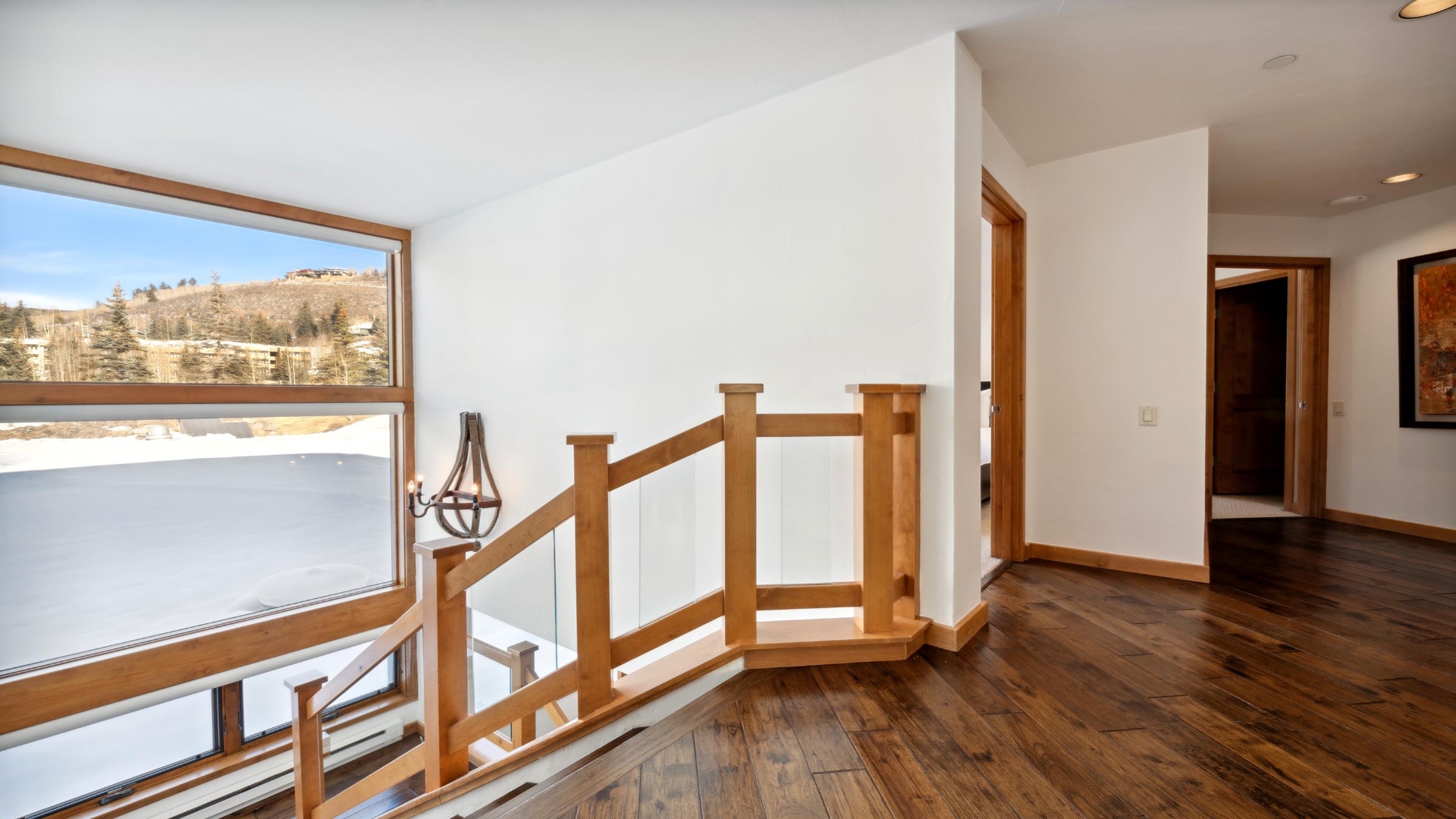 Warm wood accents frame your mountain views through expansive windows, flooding this open hallway with natural light and serene hillside vistas.