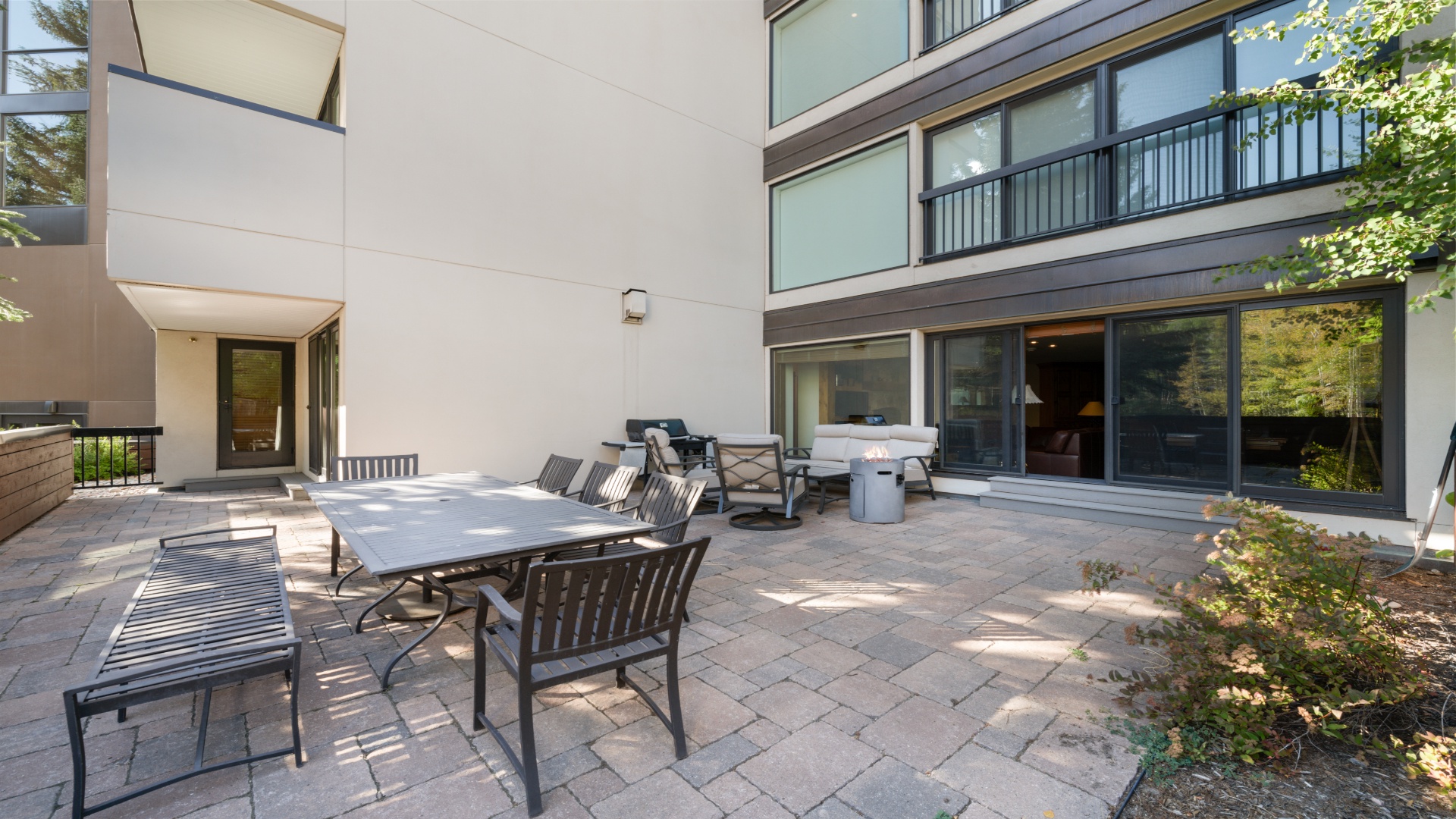 Modern multi-level property with spacious paved patio, contemporary architecture, and surrounding greenery creating a peaceful outdoor retreat.