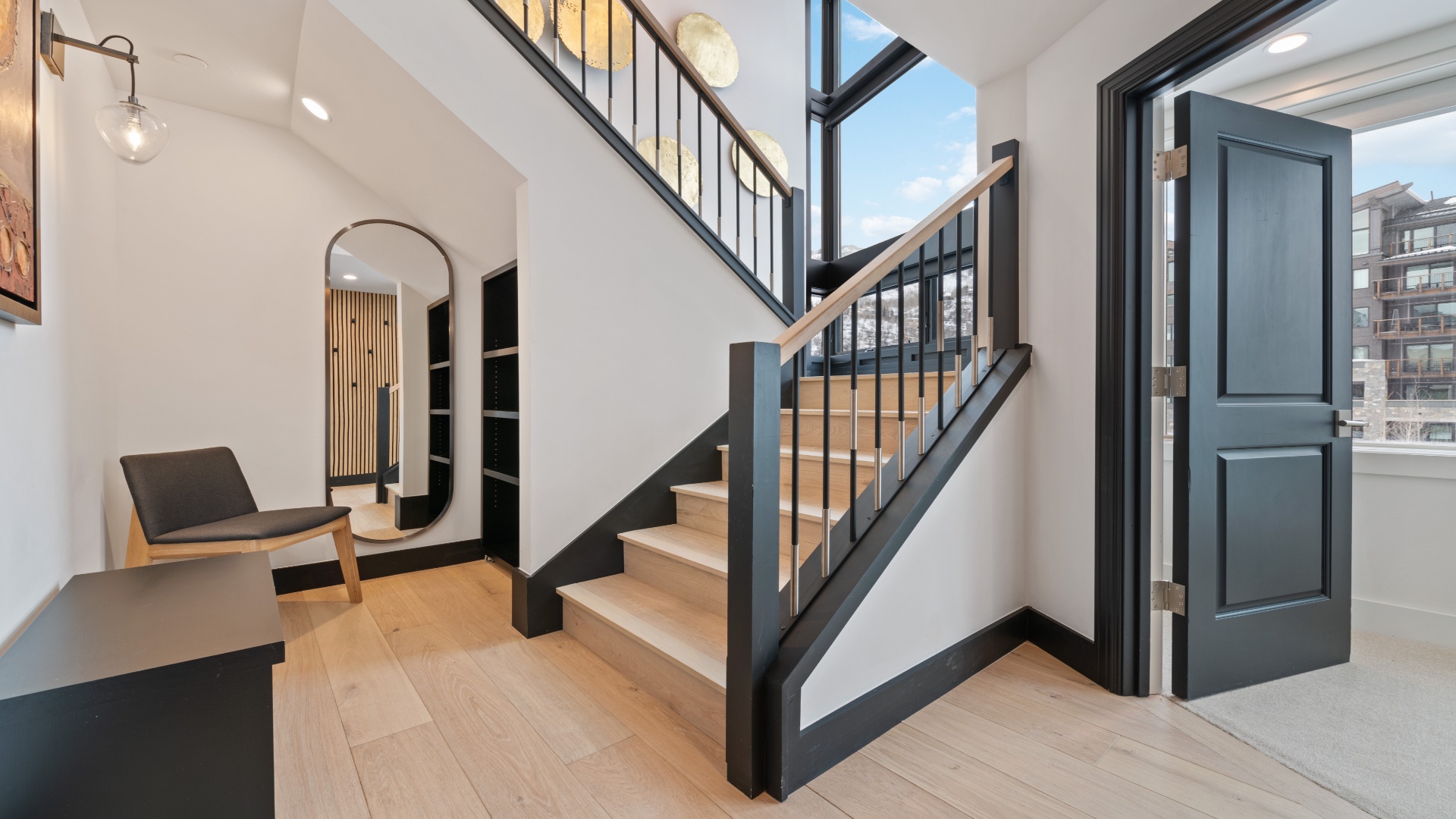 Step into a light-filled entry with soaring ceilings, sleek stairs, and warm wood floors that welcome you home in modern style.