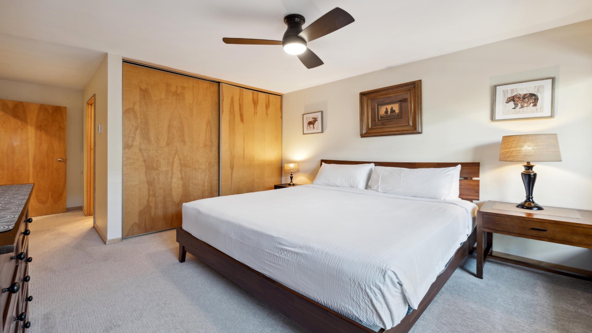 Slip into crisp white linens under a gentle ceiling fan, with rustic wildlife art and soft lamplight setting the mood for your peaceful mountain retreat.