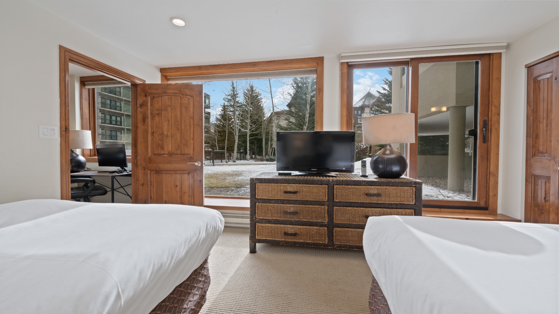 Rest easy in your cozy bedroom with two comfortable beds, charming wicker furnishings, and stunning mountain views right from your window. Step outside to explore snowy trails just beyond your door.