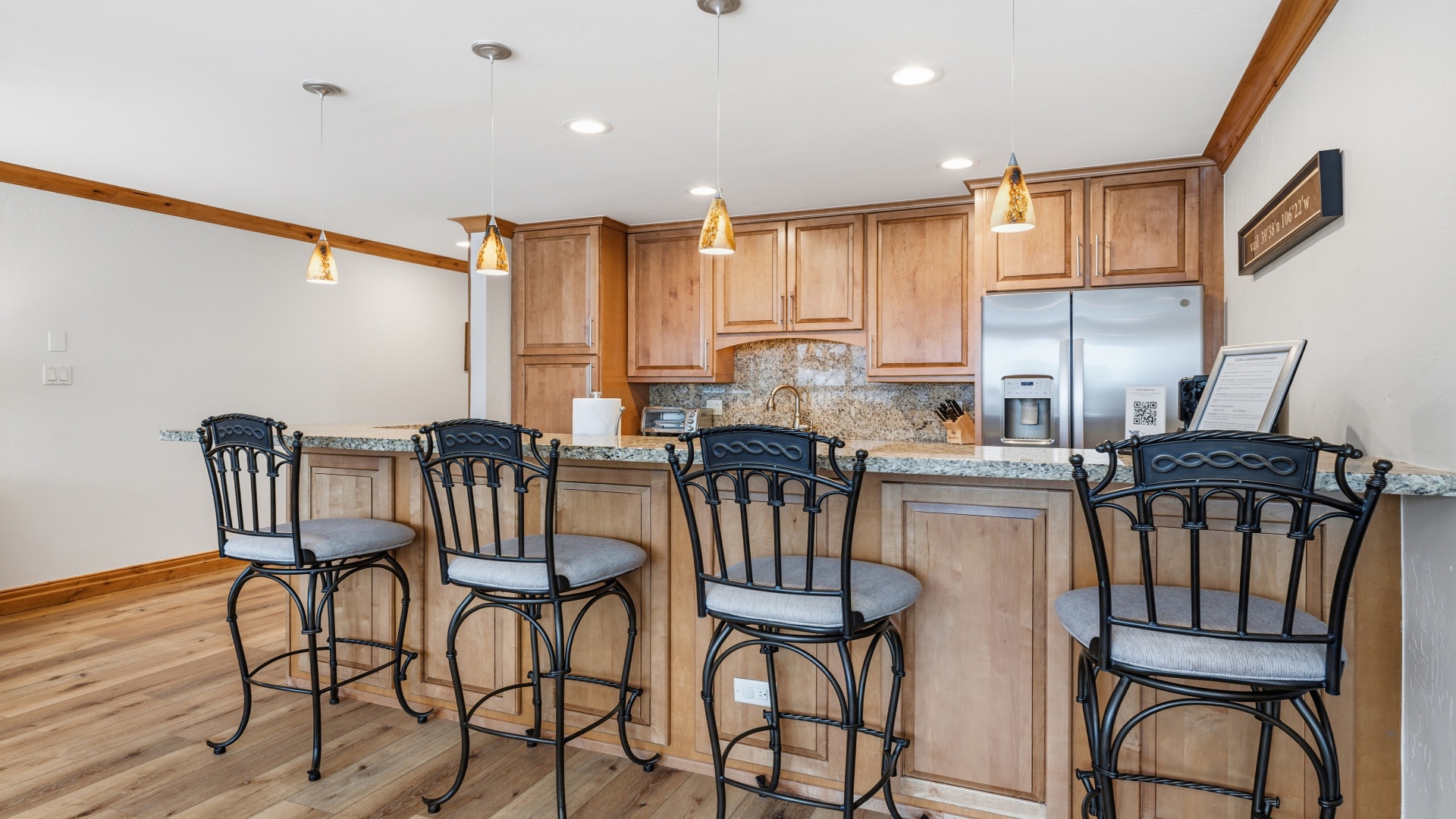 Settle into the breakfast bar for morning coffee or evening cocktails—warm wood cabinetry, granite counters, and pendant lighting create your perfect gathering spot.