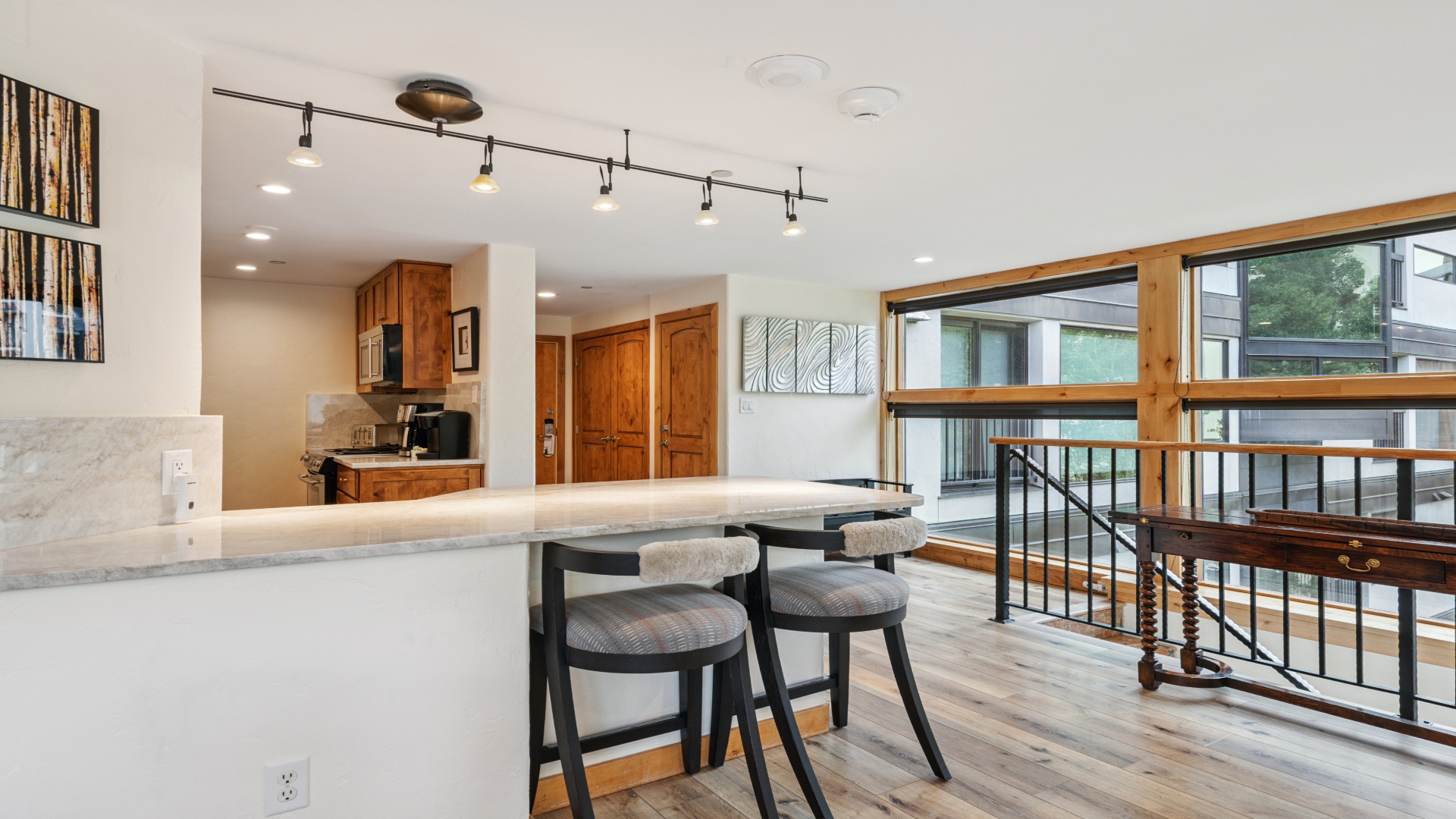 Your bright open space awaits with a sleek marble breakfast bar, warm wood accents, and natural light pouring in through expansive windows—perfect for morning coffee and easy conversations.